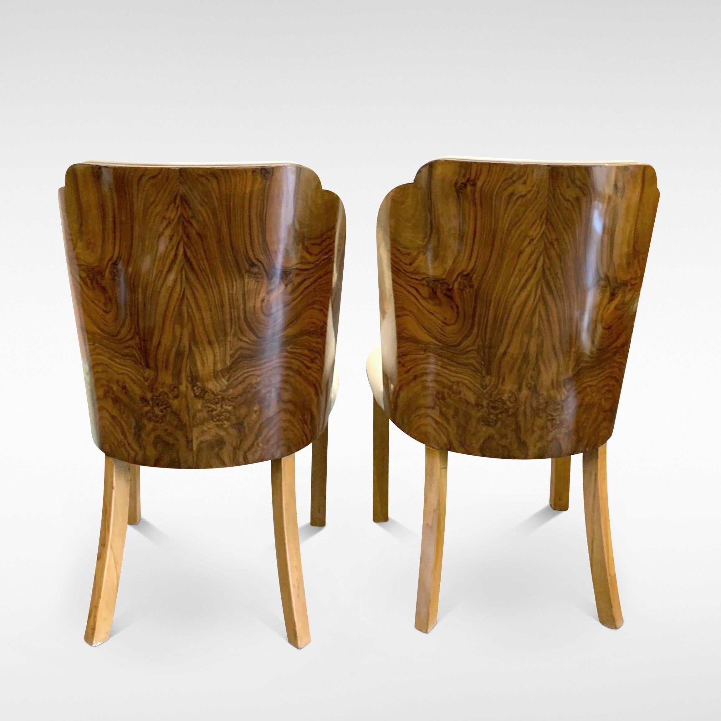 The work of the Epstein family represented a pinnacle of style and quality in English Art Deco furniture. This is a pair of iconic Epstein Art Deco Cloud Side or Dining chairs in figured Walnut and upholstered in leather.
  