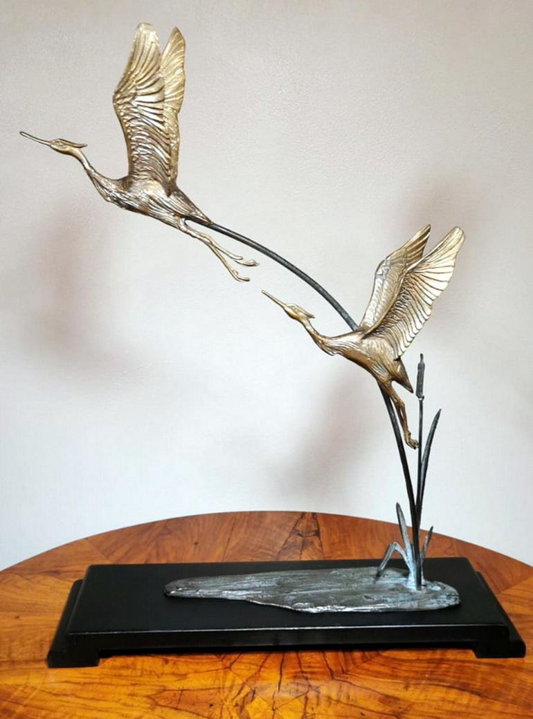 Beautiful and engaging representation of two herons taking flight from a pond; the animals have been realized with a meticulous microfusion in bronze, then gilded, that has succeeded in highlighting all the details; to make their flight more real,