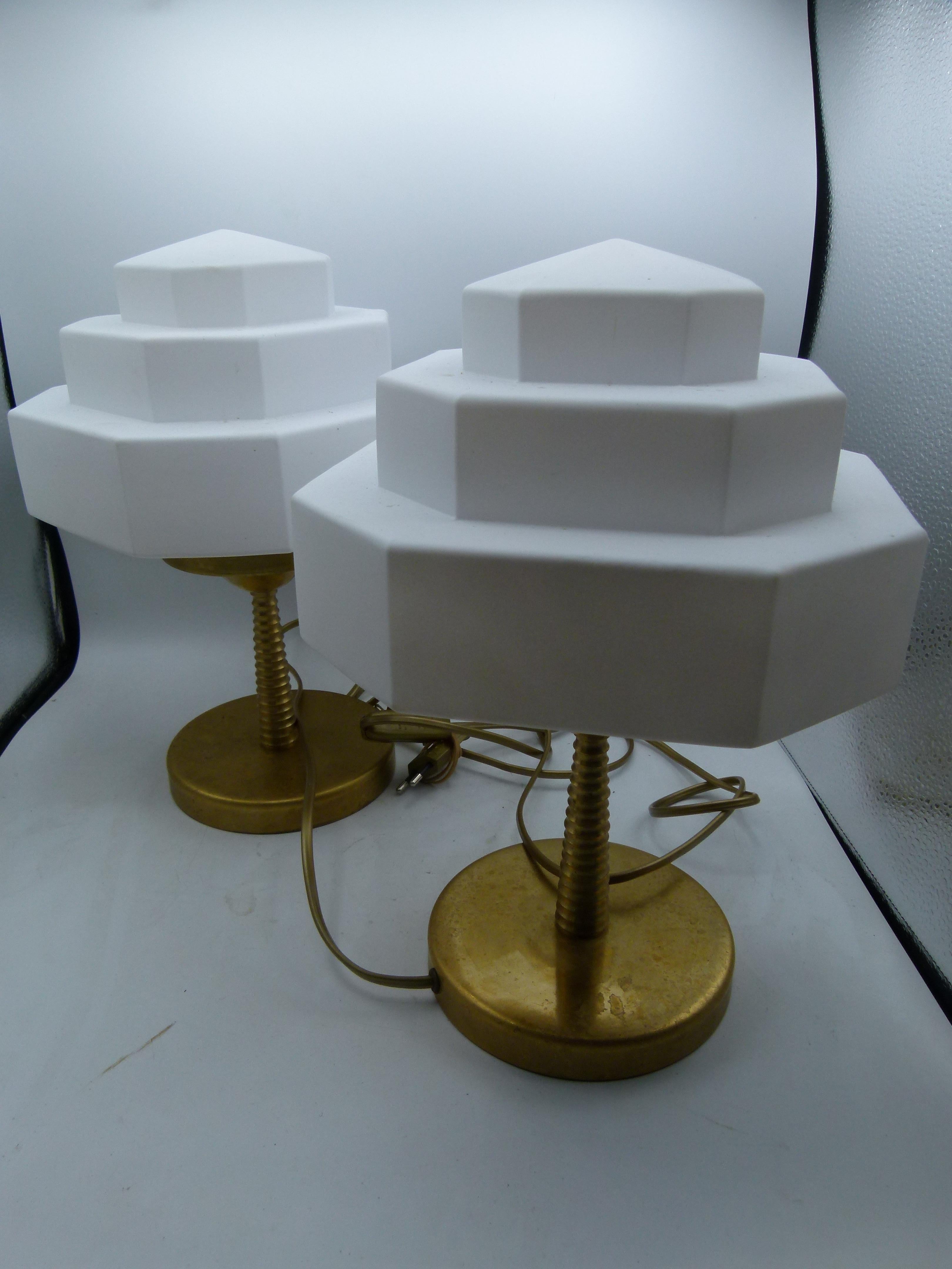 Art Deco pair of table lamps. The lamp comprises three stepped hexagonal shaped white glass shade and a brass base. An elegant table lamps that will bring a nice warm light.
The lamp is wired with a EU plug