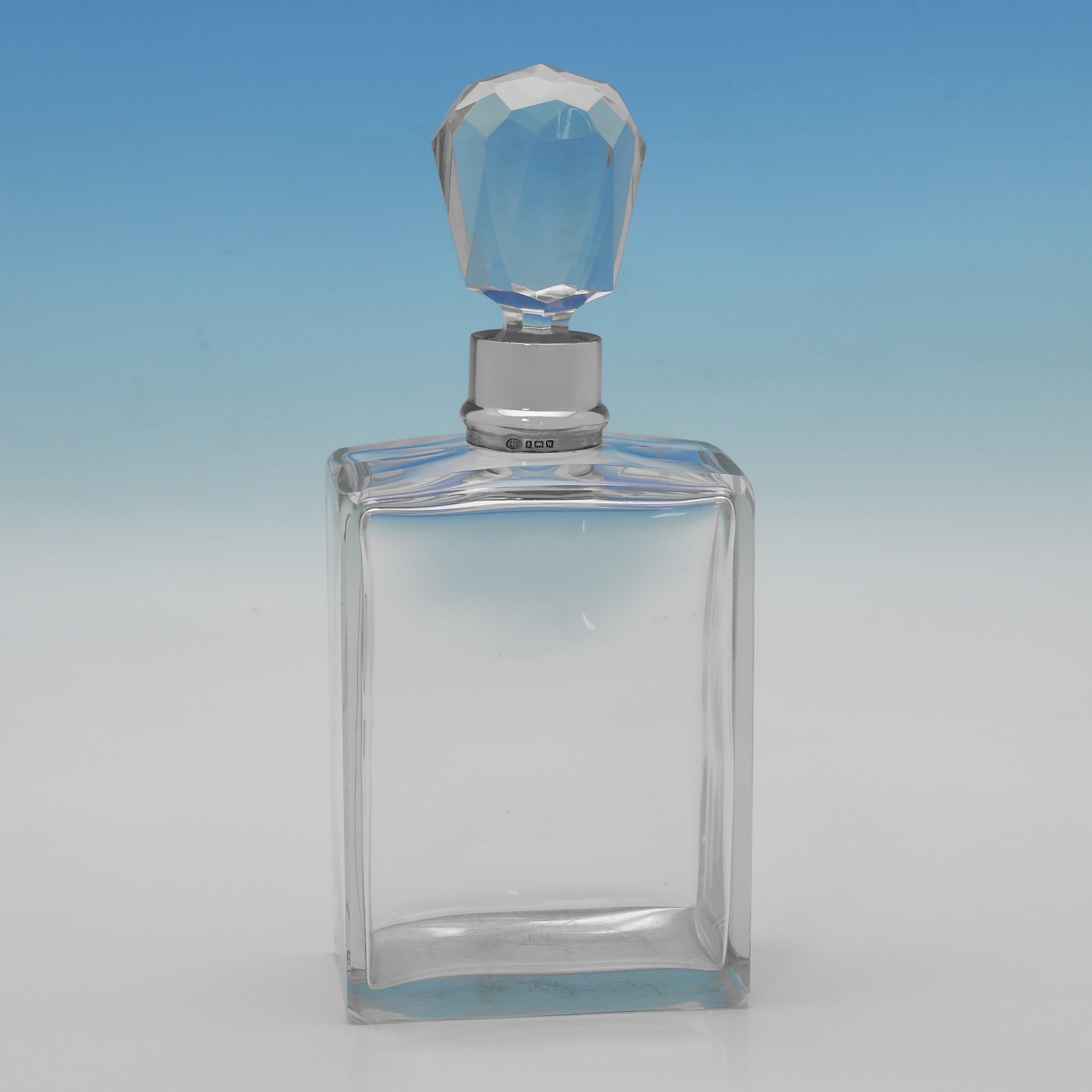 Con il marchio di Birmingham del 1921 di Hukin and Heath, questa elegante coppia di decanter in vetro antico e argento sterling del periodo George V è in stile art déco, con corpo quadrato e tappi sfaccettati. Ogni decanter misura 10,25