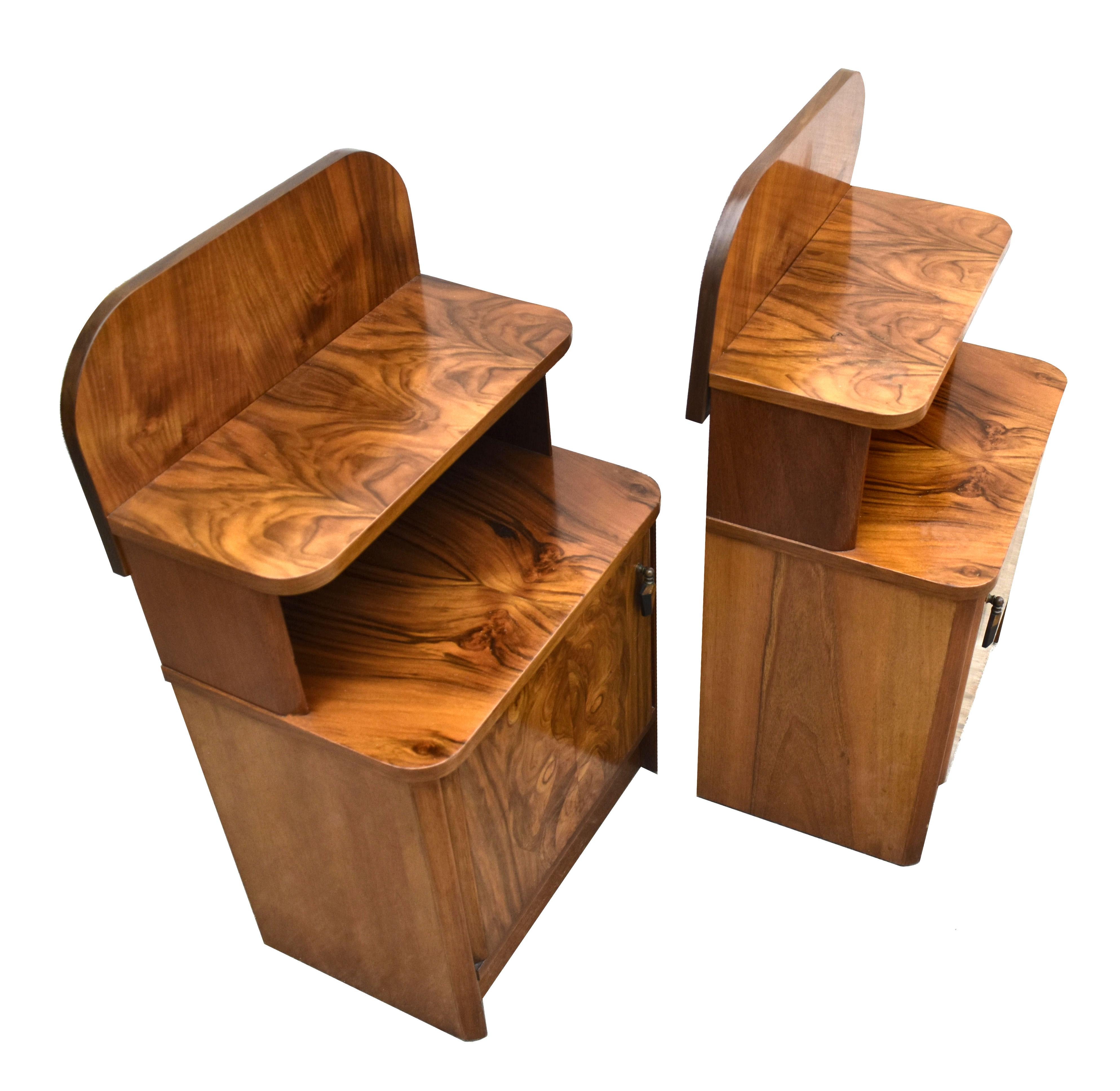 A very attractive 1930s Art Deco matching pair of highly figured walnut bedside tables. The veneers are particularly attractive. Both have an open top two tier shelf and a cupboard area below which is generously sized storage . All finished off with