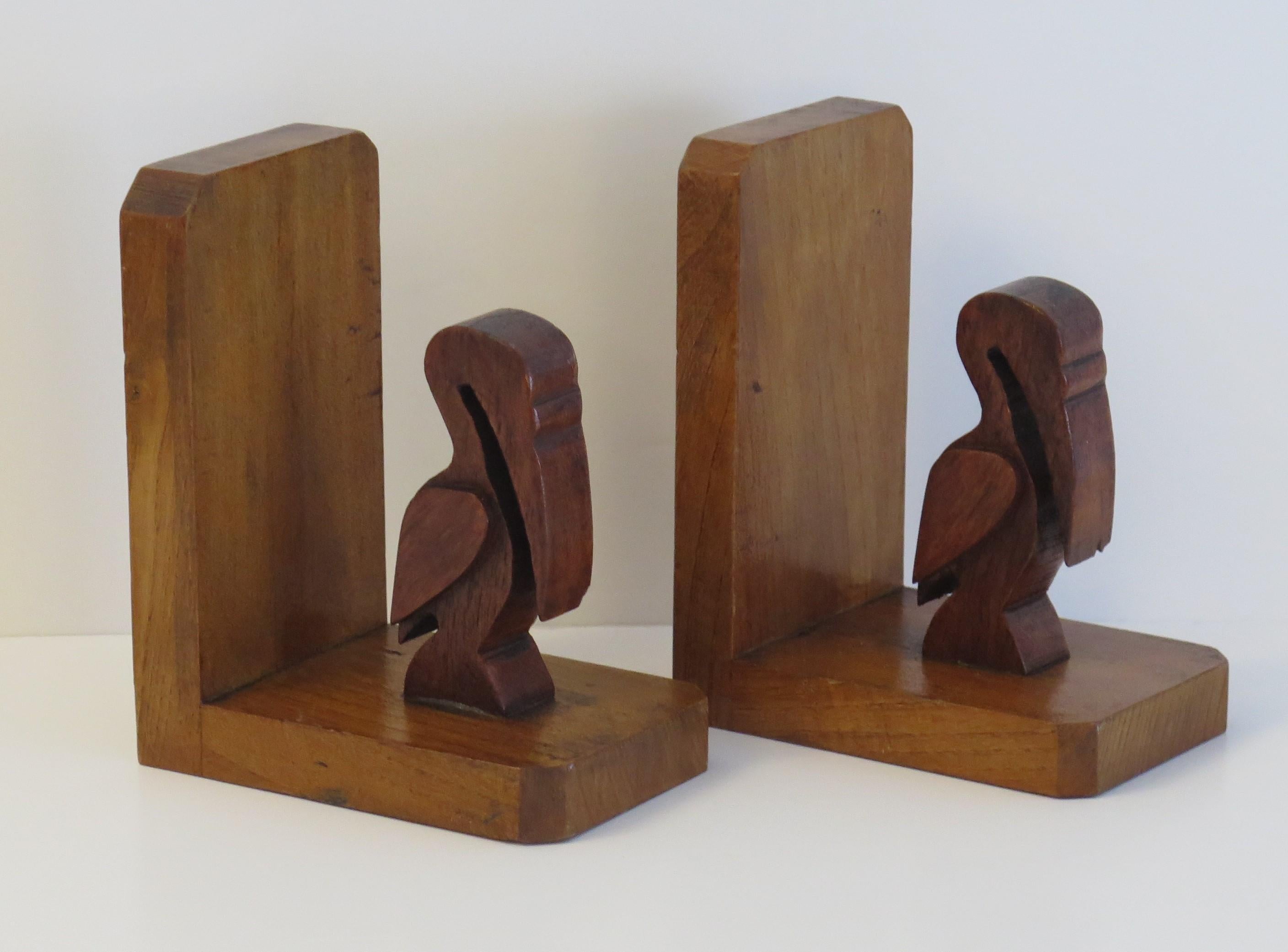 These are a good pair of Art Deco period, Book ends of two Pelicans hand carved in wood. 

Each stylised pelican has been well hand carved in a dark hardwood and stands on a base frame of a lighter contrasting wood, all with a hand polished