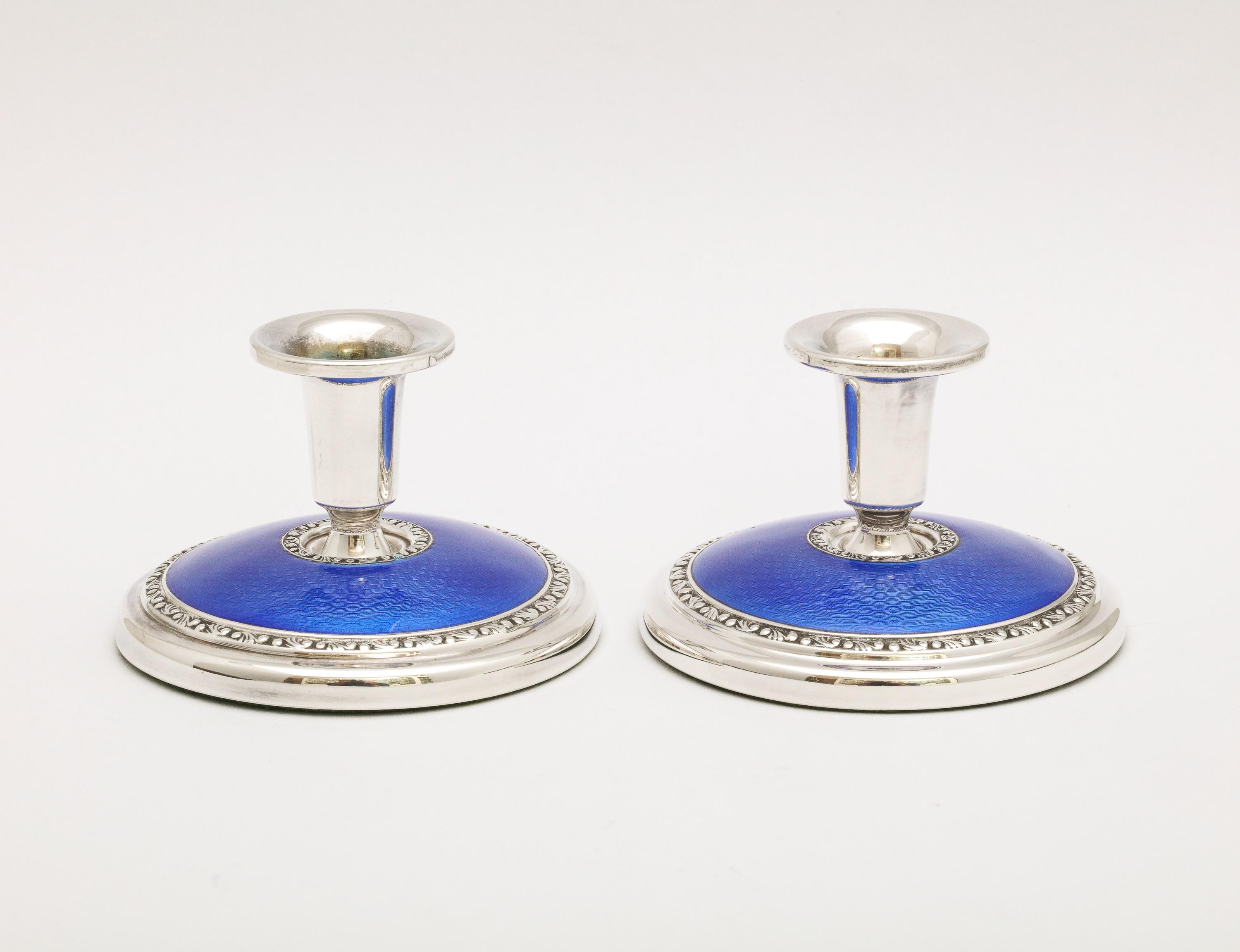 Pair of Art Deco sterling silver and dark blue guilloche enamel candlesticks, Oslo, Norway, Ca. 1930's, Norsk Silwarreindustri - makers. Each candlestick measures 2 inches high x 2 3/4 inches diameter. Weighted bases. Underside of each base is