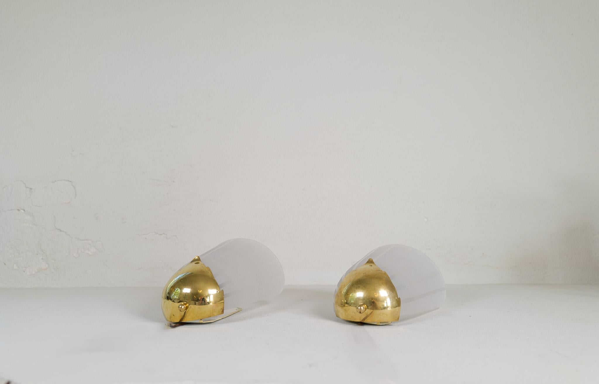A pair of wall light made in Sweden with that elegant Swedish Grace touching the Art Deco period. 
Wonderfully sculpted glass with the lower part covered in brass details. 

Good vintage condition. Brass with patinated stains. 

Dimensions: Height