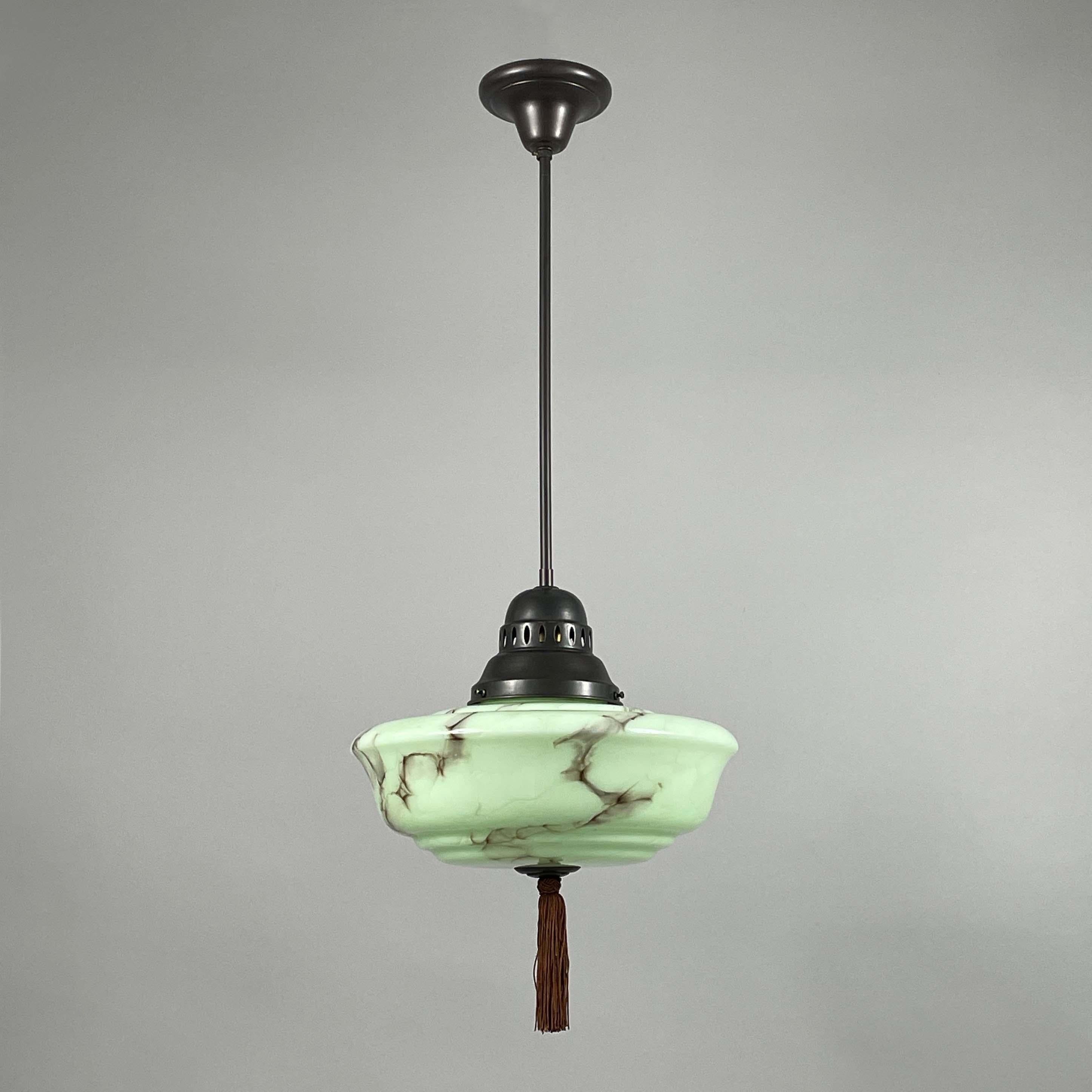 This Art Deco pendant was designed and manufactured in Germany in the 1930s during the Bauhaus period.

The light is characterized by its streamlined, functional design typical of the movement. The light features a smooth, translucent green opaline