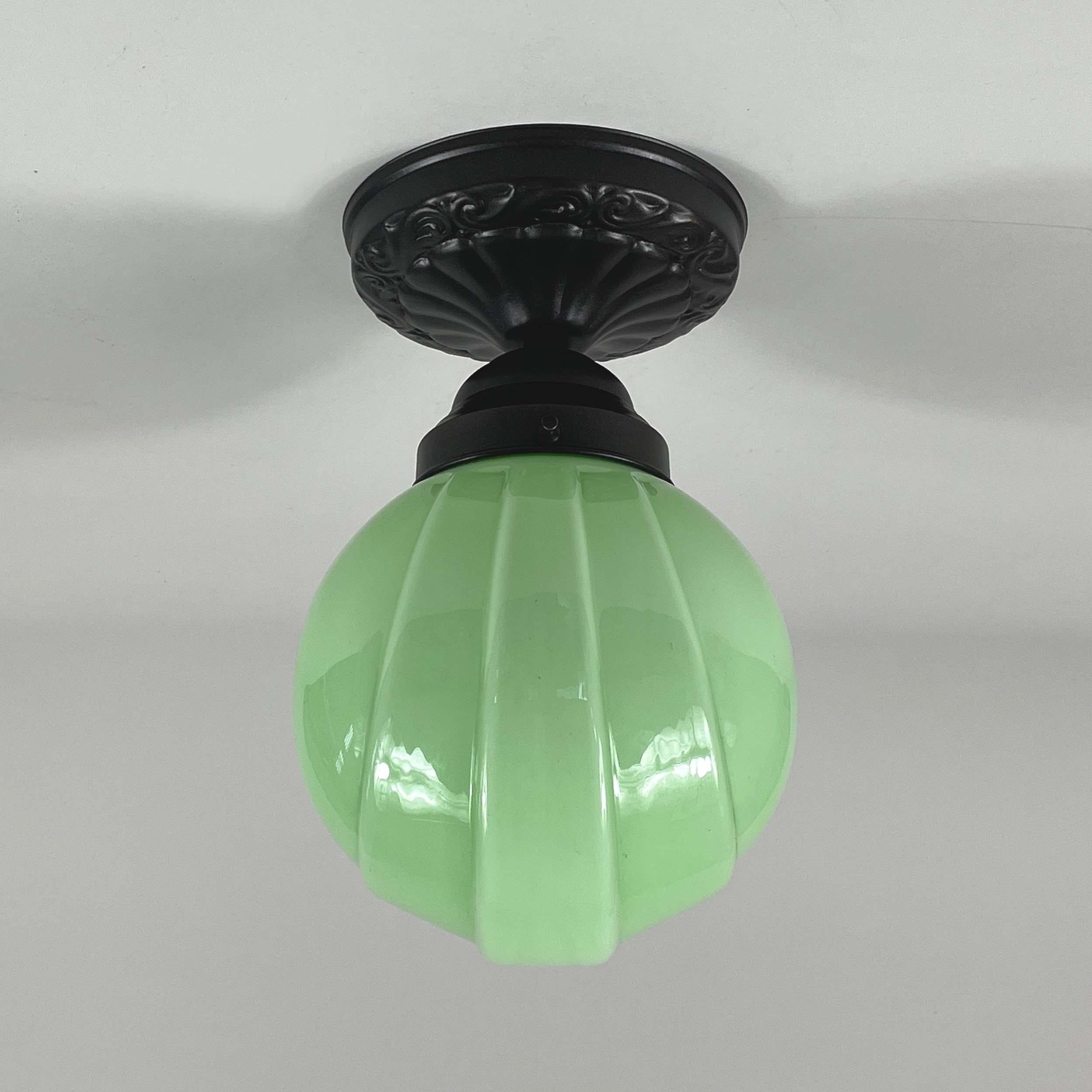 This Art Deco flush mount was designed and manufactured in Germany in the 1920s to 1930s. It features a pale green opaline lampshade and bronzed / burnished hardware.

The light requires one E26 / E27 bulb (LED recommended).

Diameter of canopy is