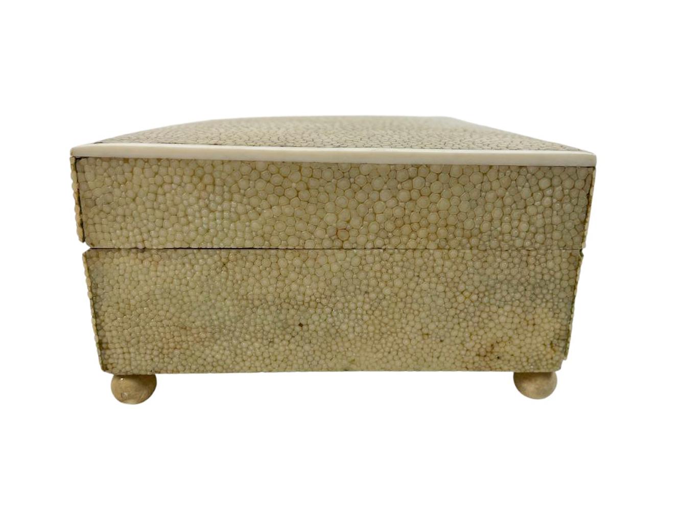Caja Art Decó forrada de piel de zapa teñida de verde pálido, con tapa abatible ribeteada en hueso y elevada sobre patas de bola. La parte inferior lleva el sello 