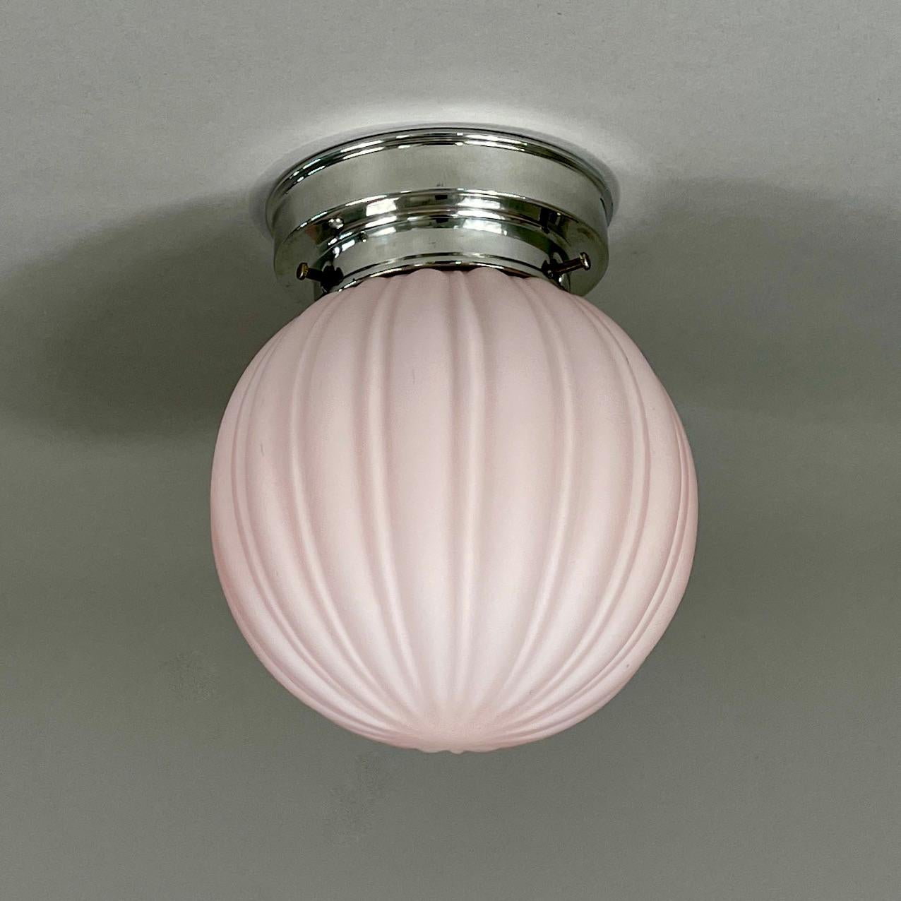 Este pequeño empotrable se diseñó y fabricó en Suecia en la década de 1940. 

La luz presenta un delicado globo de cristal esmerilado rosa con estrías verticales que crean un aspecto suave y texturizado. El globo está montado en un elegante
