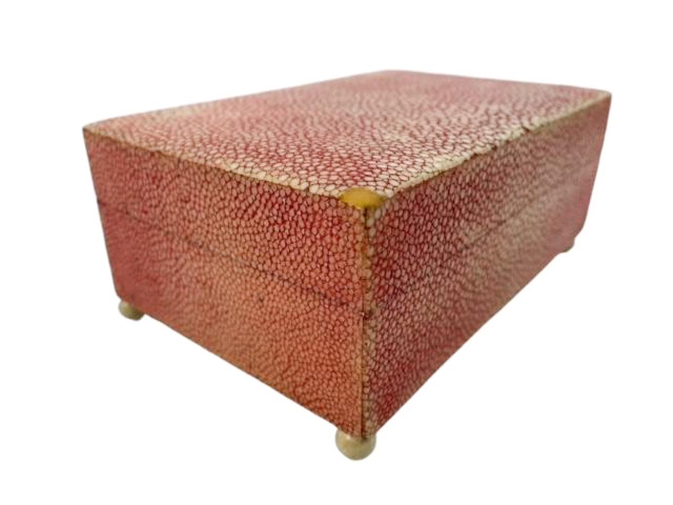 Caja Art Decó de piel de zapa teñida de rosa sobre madera, la parte superior con bordes ligeramente redondeados encaja perfectamente sobre un reborde interior y se sujeta con bisagras de apoyo, todo ello elevado sobre pies de bola.