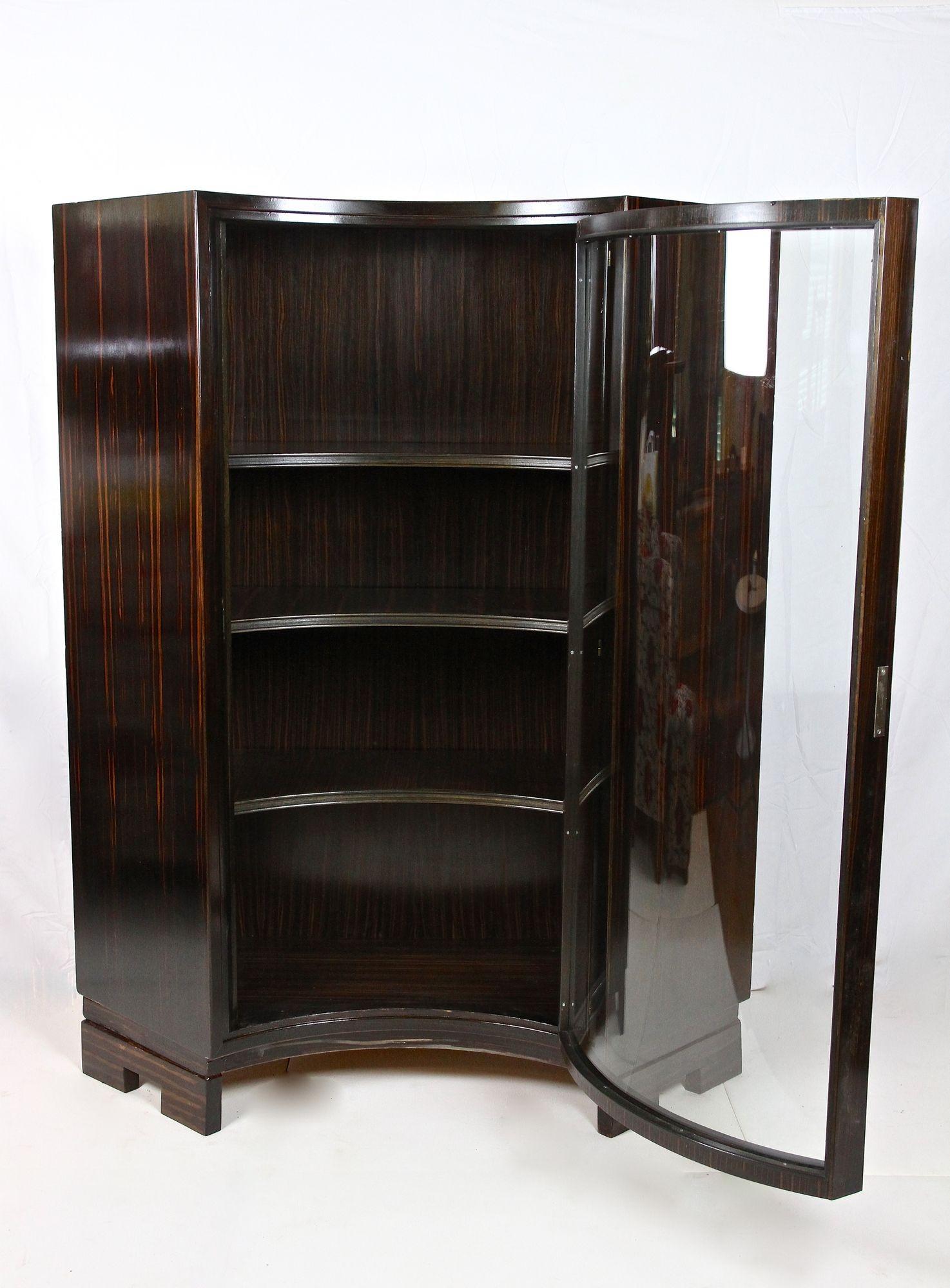 Stunning Art Deco palisander display cabinet or corner cabinet from the famous period in France around 1930. This absolutely amazing Art Deco vitrine cabinet impresses with its extraordinary curved design. Due its smart construction it can be used