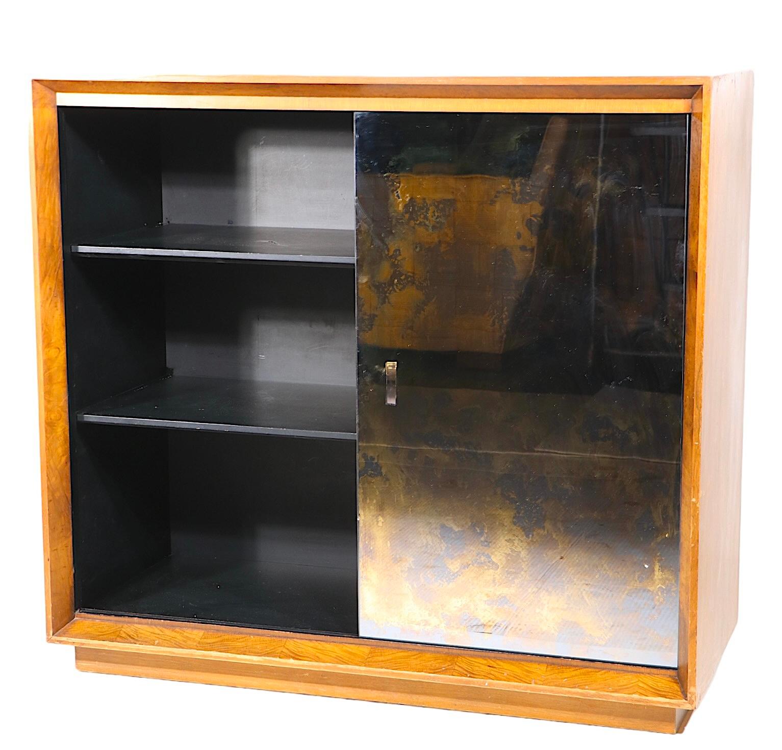 Voguish, chic and sophisticated storage cabinet designed by Gilbert Rohde for Herman Miller as part of the sought after Palladio series, c. 1940’s.
The piece features a walnut case, with burl veneer picture frame molding that surrounds the gold and