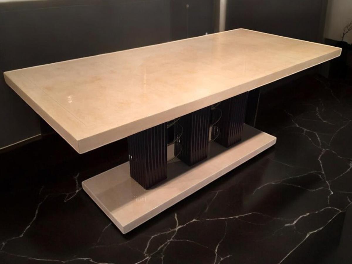 Very rare and exceptional Art Deco parchment table, with top and base in parchment veneer, the table top is supported by three wooden columns characterizedby a refined grooved design,the splendid brass decorations that act as a connection between