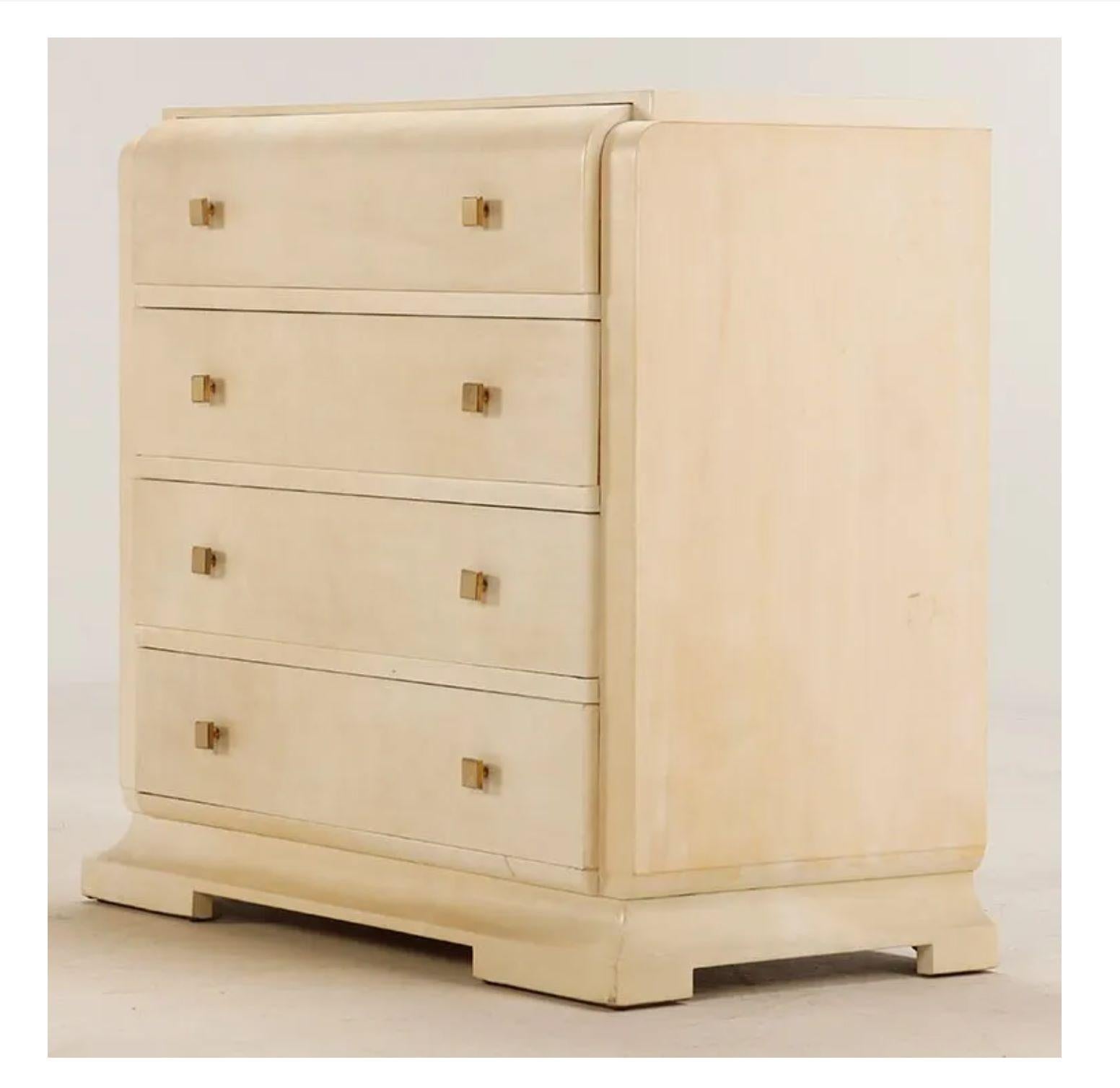 1940s Art Deco parchment dresser in the style of Samuel Marx, with square brass knobs. Four (4) drawers sit atop an architectural base, the top drawer has a beautiful curved waterfall detail at the top. 