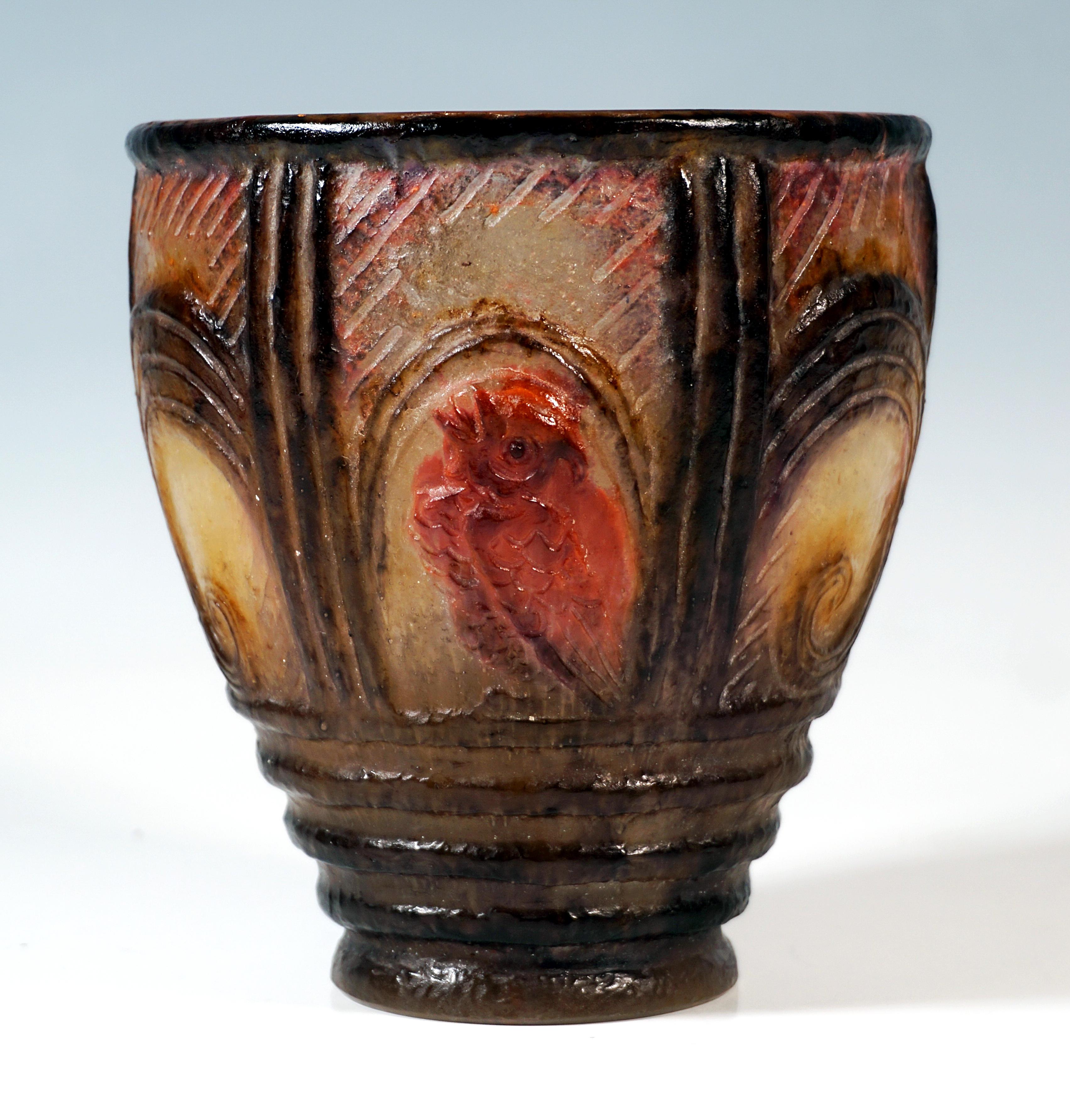 Funnel-shaped curved vase on a round base made of translucent pâte de verre with coloured powder infusions in black, yellow, burgundy red, and violet, with four horizontal ribs in the base area, wall above divided into 6 segments by tripple vertical