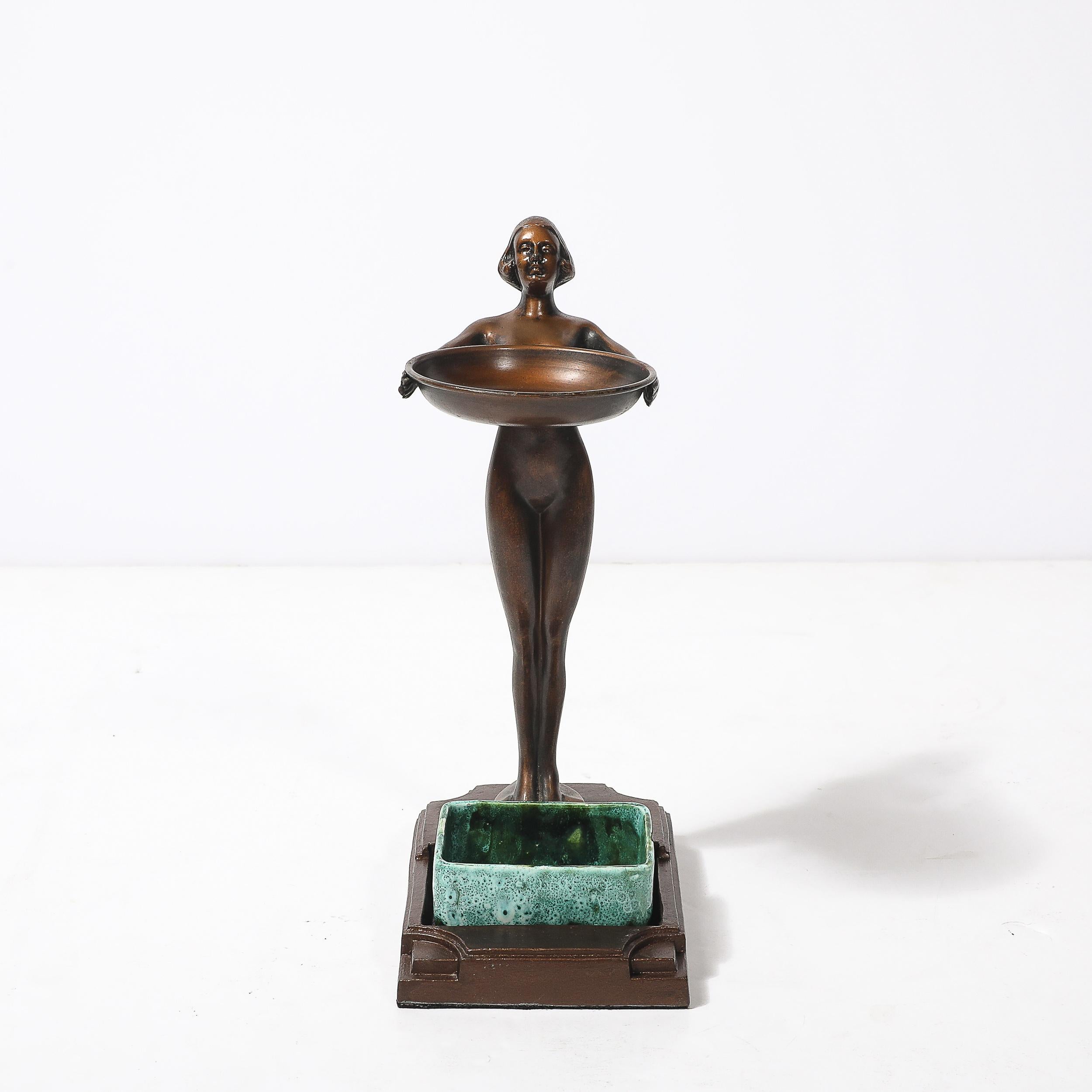 This rare Art Deco smoking stand by FrankArts, crafted in the United States circa 1935, exemplifies the refined glamour and functional elegance of the Art Deco era. 

The stand features a slender, patinated bronze base with a nude woman standing
