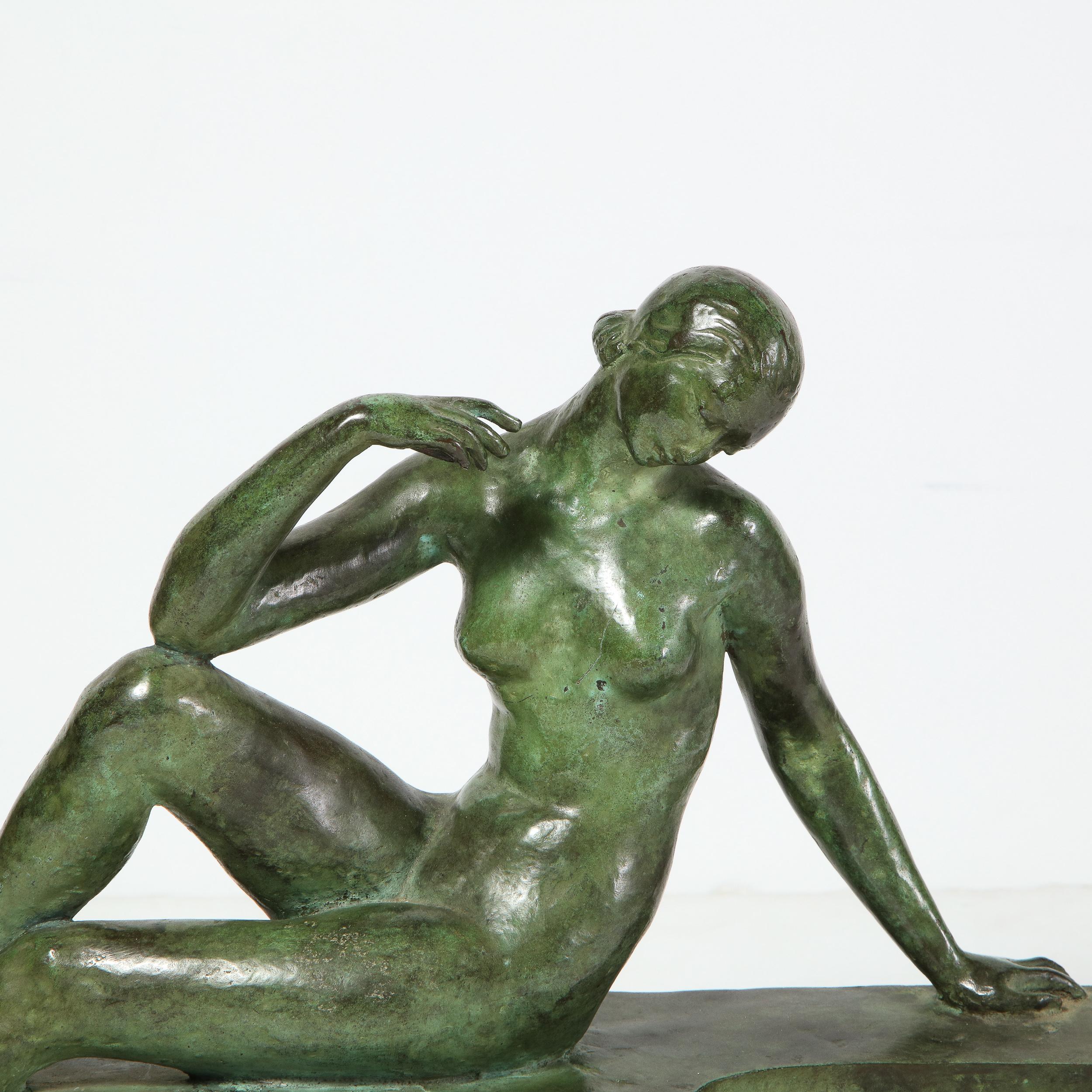 This stunning Art Deco bronze sculpture was realized by the esteemed 20th century sculptor Marguerite Anne de Blonay in France, circa 1930. It features an elegantly reclined female figure with one arm outstretched and a leg perched upon a pedestal.