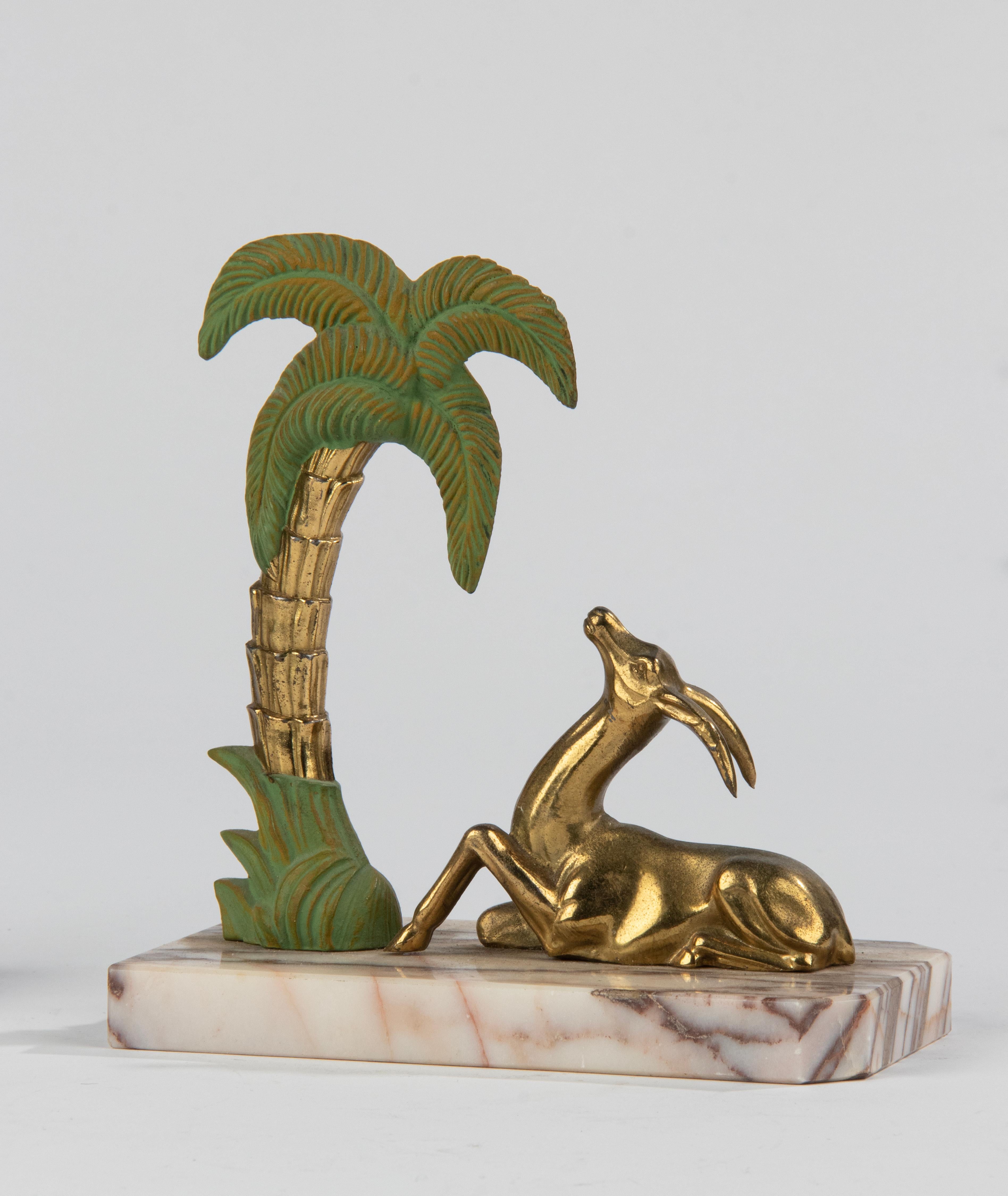 A lovely pair of Art Deco bookends, with images of gazelle / deer under a palm tree. The plinth is made of Breccia marble. The figurines are made of zinc alloy, gold and green patinated. The marble and the figurines are in good condition. Made in