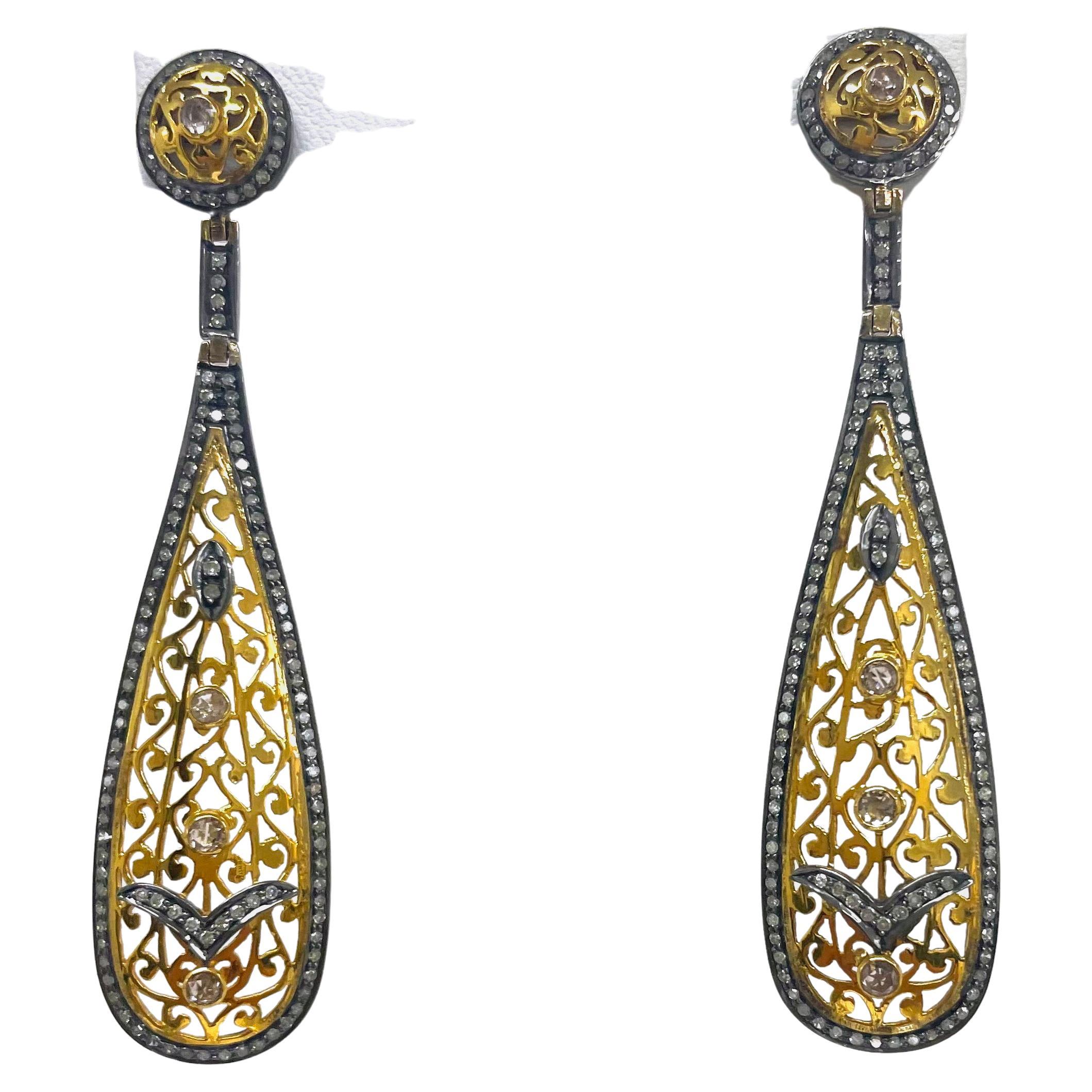 Description
Beautiful and feminine Art Deco style earrings intricately detailed with 14k yellow gold filigree and embellished with rose cut champagne diamonds. The contrast of yellow gold with medium-gray rhodium sterling silver set pave diamonds
