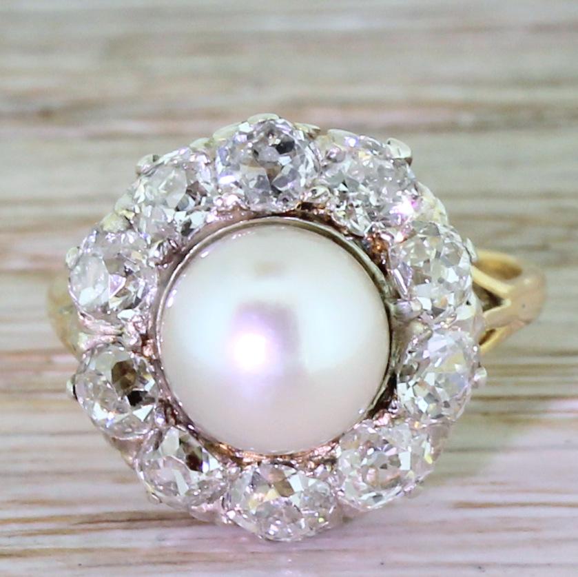 A stunning pearl and old cut diamond cluster. The pearl is a smooth, creamy lustre and is surrounded by the white and lovely old mine cut diamonds which are claw set in a pierced gallery. The trip-split shoulders lead to slim 18k gold shank. A real