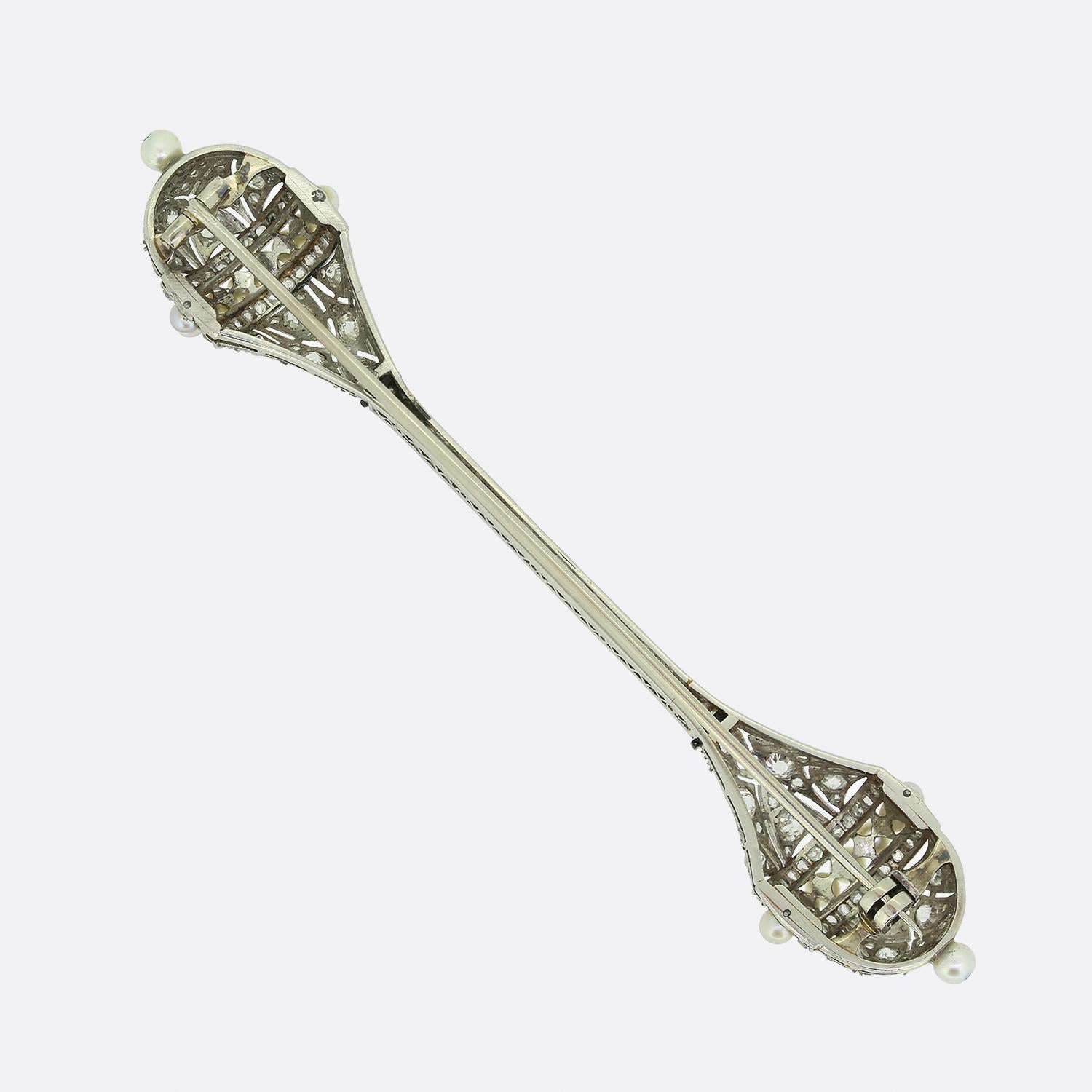 Here we have a fabulous bar brooch crafted during from the pinnacle of the Art Deco movement. This platinum piece showcases a centralised bar section filled with a single row of round faceted old cut diamonds which plays host to two identically