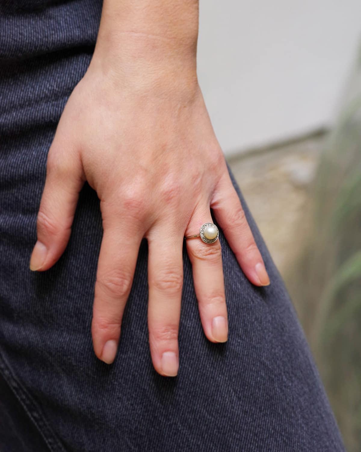 Bague Art Deco perle diamant en or 18k. Bague circulaire centrée sur une perle de 7 mm, entourée de 16 diamants taillés en rose. Les bagues de cette période sont également appelées 