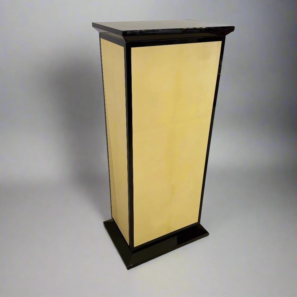 Elégante finition laquée crème et noire avec détails parcheminés sur les quatre côtés. Sa forme rectangulaire, avec une plateforme supérieure et une base légèrement plus grandes, lui confère une sophistication subtile. Fabriqué en France vers 1930.