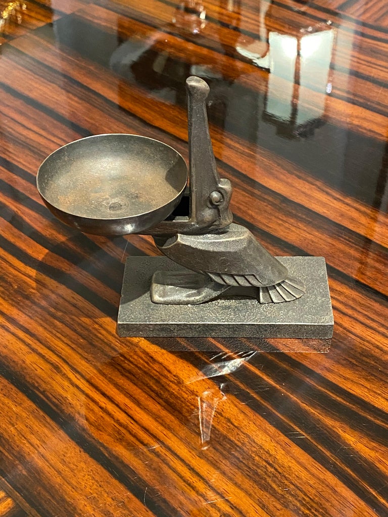Art Deco Edgar Brandt patinated iron ashtray/coin tray taking
the form of a pelican, mouth open wide, holding a bowl.
Made in France, 
circa 1925.
Signature: 