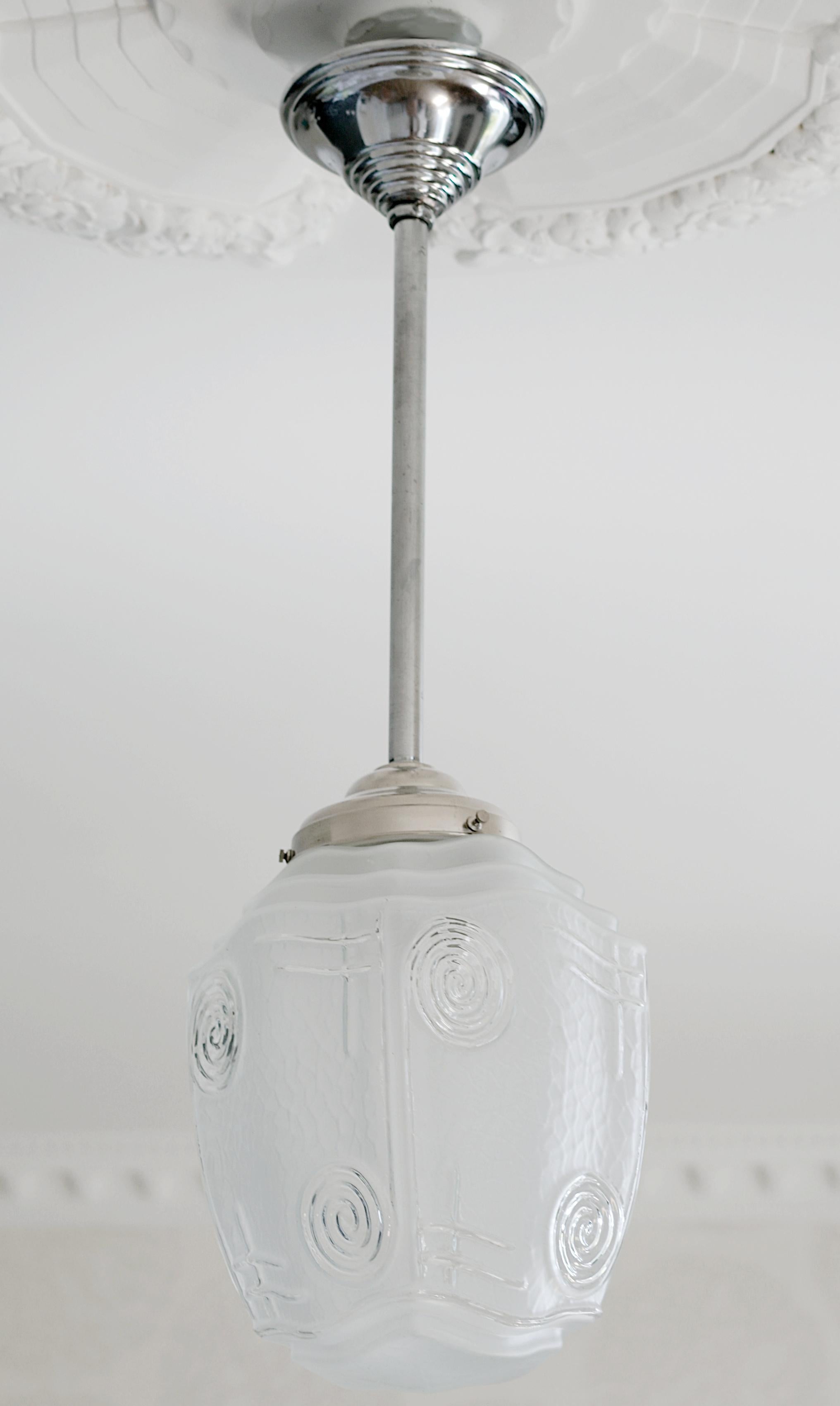 Questo elegante lampadario a sospensione francese in stile Art Déco, risalente agli anni '20, presenta una straordinaria miscela di materiali in vetro e ottone. Il design raffinato cattura l'essenza dell'epoca Art Déco con linee pulite e una