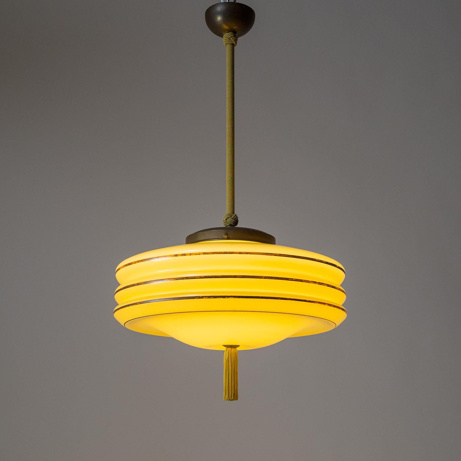 Rare Art Deco pendant with a large pastel amber colored glass diffuser, circa 1930. The glass body has a white casing inside and a very unusual tripple saturn ring shape which is emphasized by a silver paint line on each 'ring' which has darkened