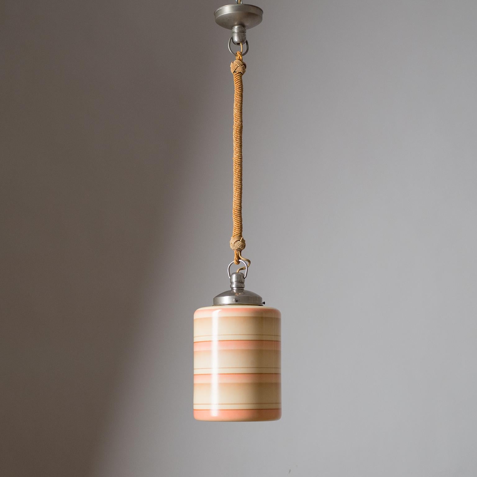 Rare Art Deco pendant or lantern, circa 1930. Suspended by a twisted cord is a cylindrical ivory-colored glass diffuser enameled with alternating stripes and gradients. Fine original condition with some light patina on the nickeled brass hardware.