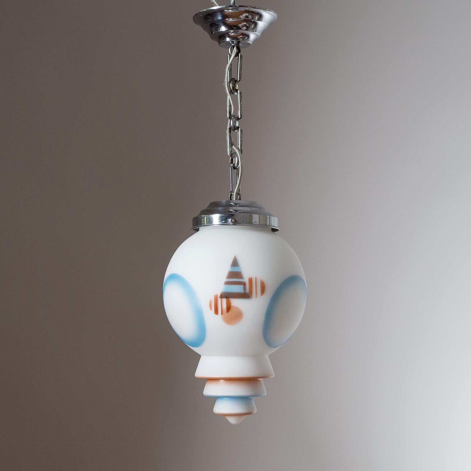 Very unique Art Deco pendant from the 1920-1930s. The 'metropolis' style tiered satin glass diffuser has enameled geometric designs in light blue and dark caramel. The hardware is chromed brass with similarly tiered canopy and glass holder. Fine
