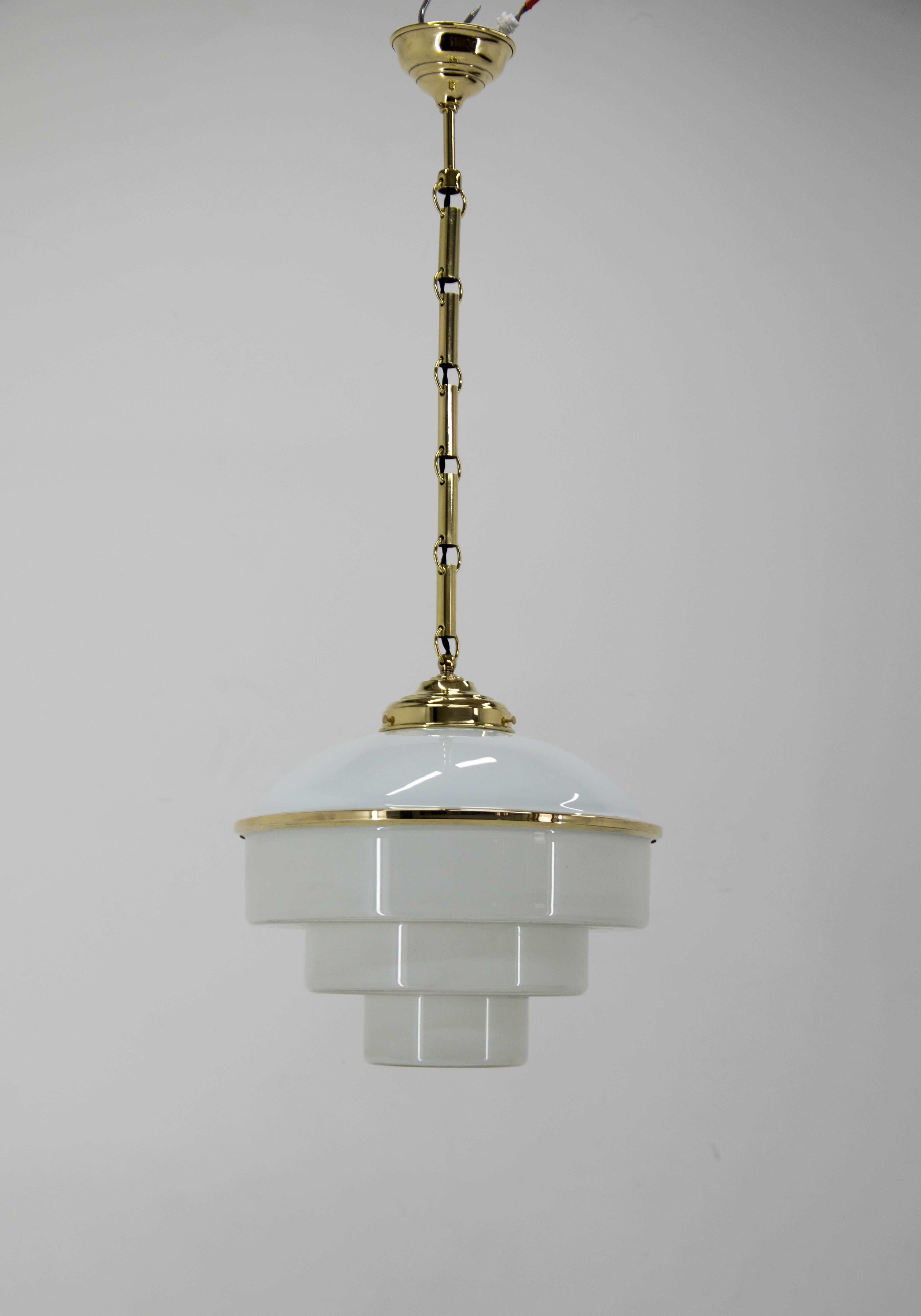 Beautiful Art Deco pendant made of brass and glass.
Upper opaline glass is connected with semitransparent bottom glass with brass ring.
Restored: polished, rewired.
1x100W, E25-E27 bulb.
US wiring compatible.