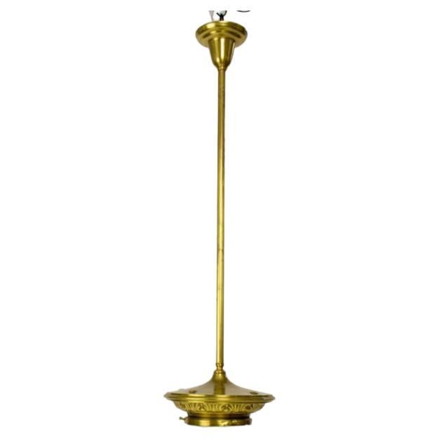 Brass pendant fixture on a rod. Fixture has ventilation holes on the top of the fitter and a decorative edge. White milk glass shade with a conical shape.

Material: brass, glass
Style: Traditional,Art Deco
Period made: early 20th