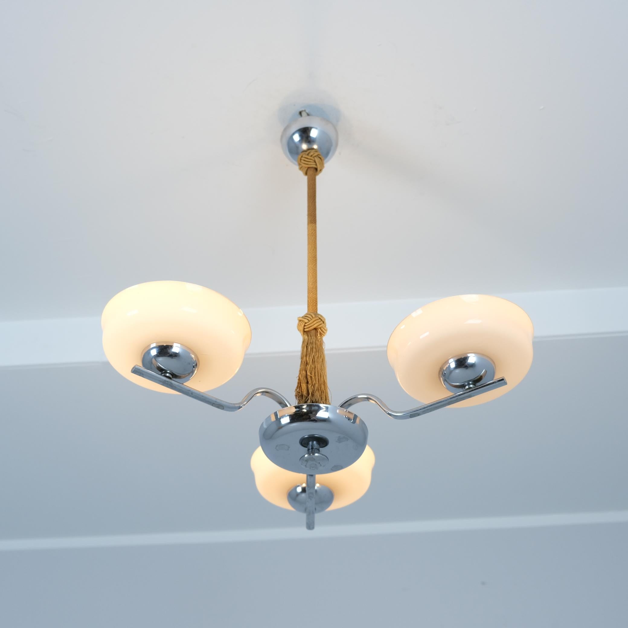 Un bel exemple de lampes finlandaises Art déco des années 1930. La lampe présente un corps en laiton lisse nickelé (peut-être chromé) avec trois bras surmontés d'abat-jour en verre soufflé et une tige recouverte d'une ficelle brune qui était souvent