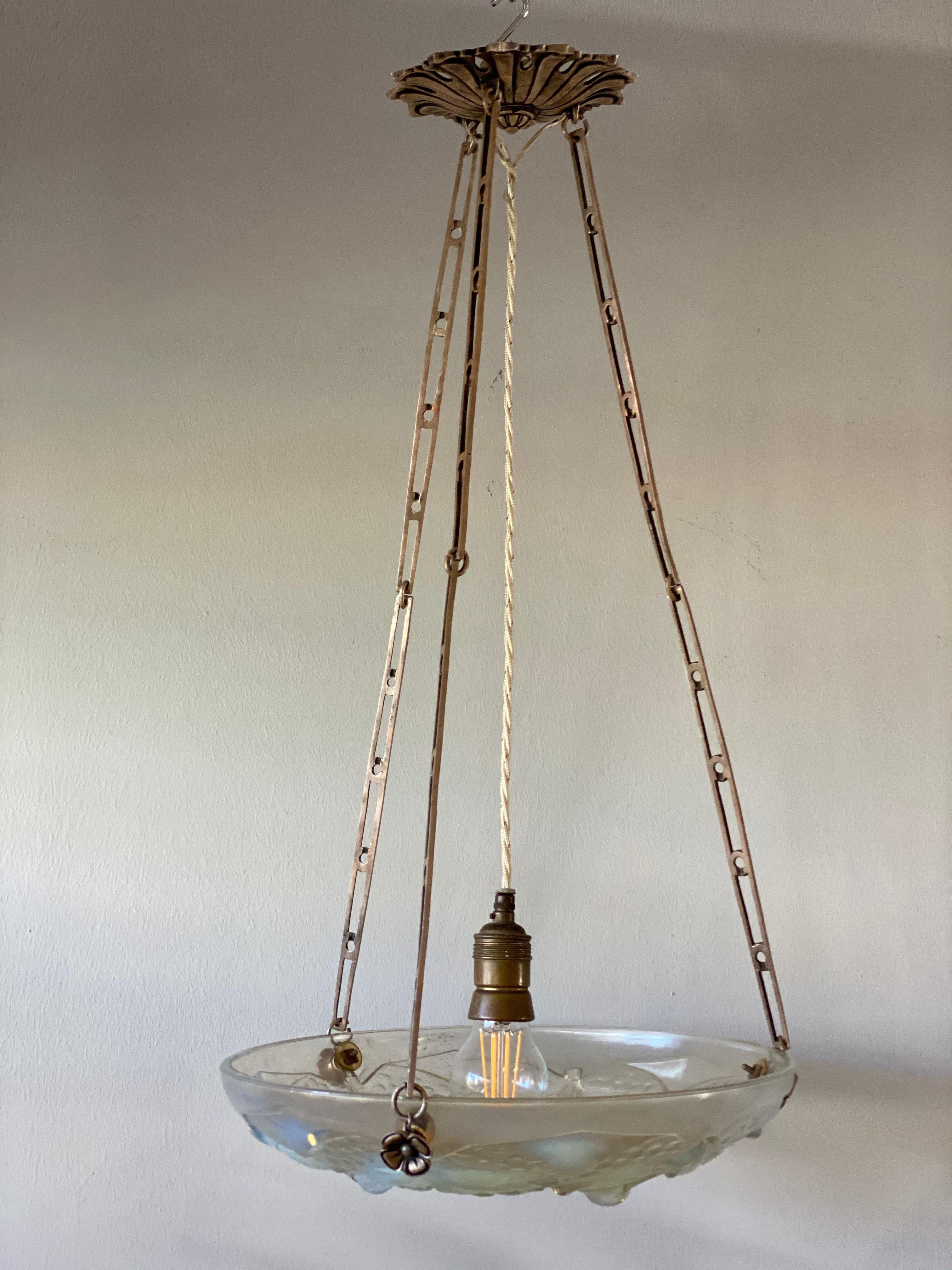 This special Art Deco pendant lamp made of opaline glass or iridescent glass enchants you in no time. The magically shimmering glass shade with cherry - decor hangs on three decorative chains made of metal. The cover of the cables and ceiling