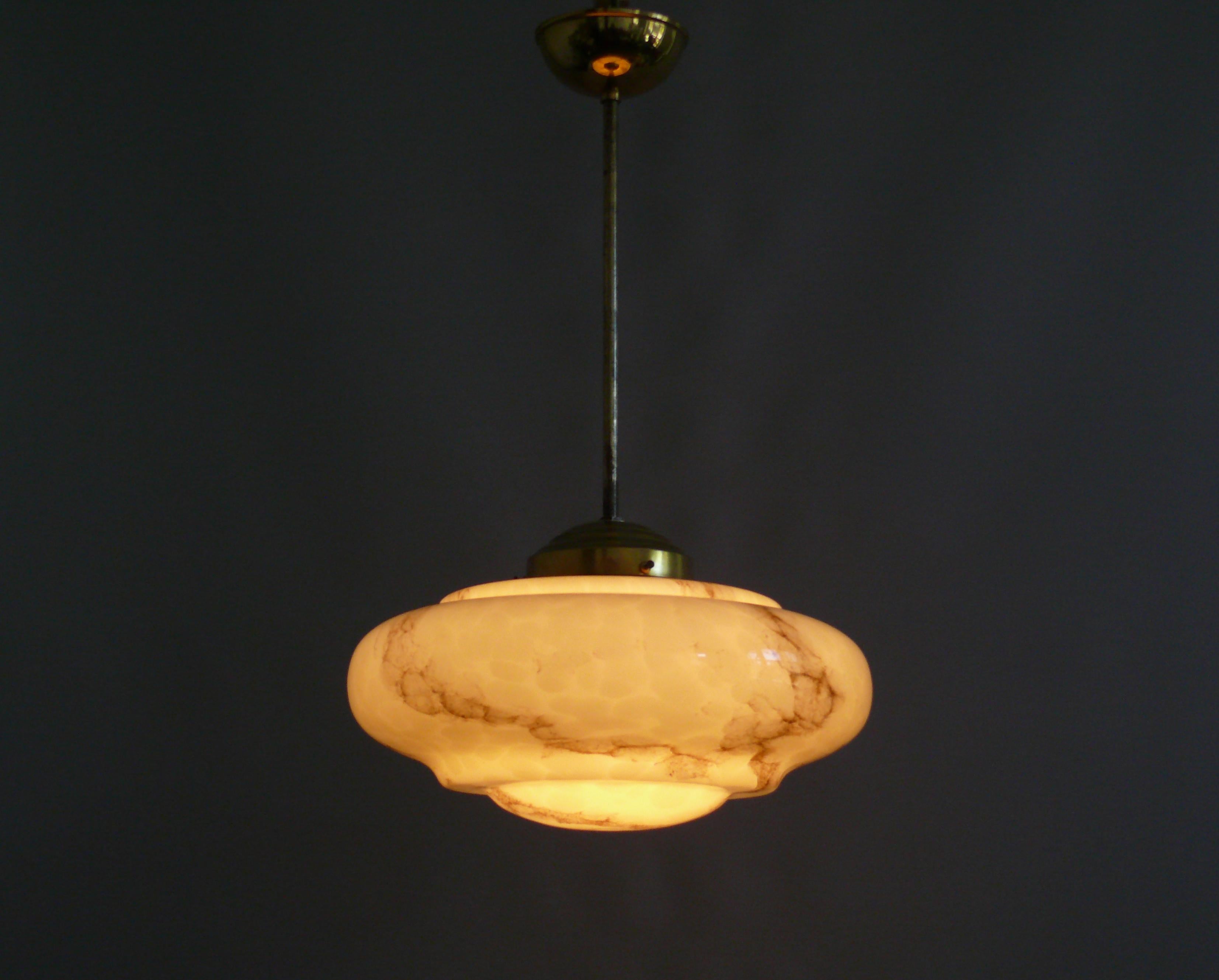 Art Deco rod pendant lamp from the 1930s - 1940s with a beautifully profiled, beige glass shade. The glass shade is marbled and is in very good condition. The suspension is made of brass and was renewed in keeping with the style from stock. The
