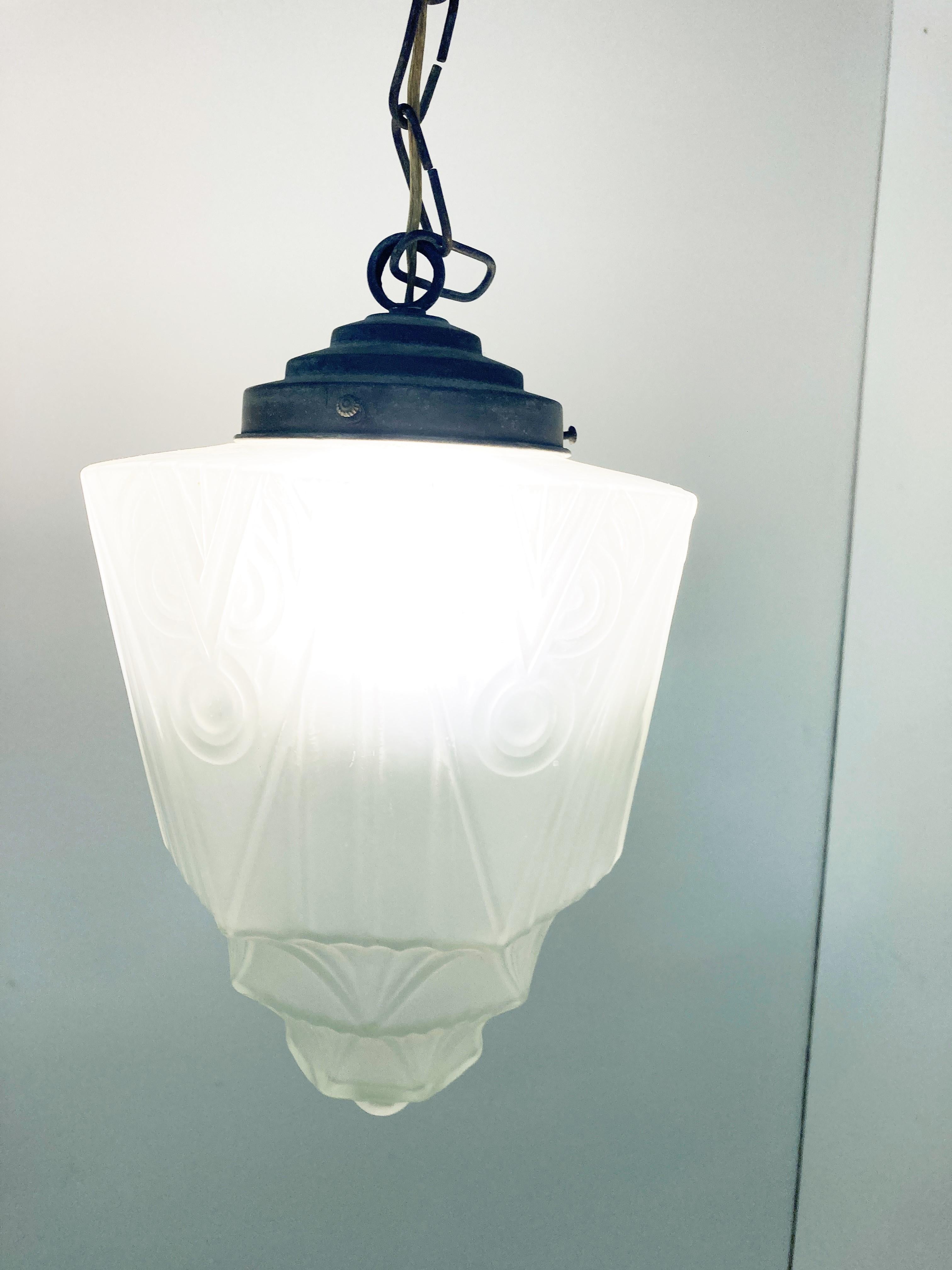 Antique Art Deco hallway pendant light.

This lamp is very typical for the Art Deco era and these lamps where usually hung in hallways or at front door entrances

The lamp has the original copper shade holder with ceiling cap.

The shade emits