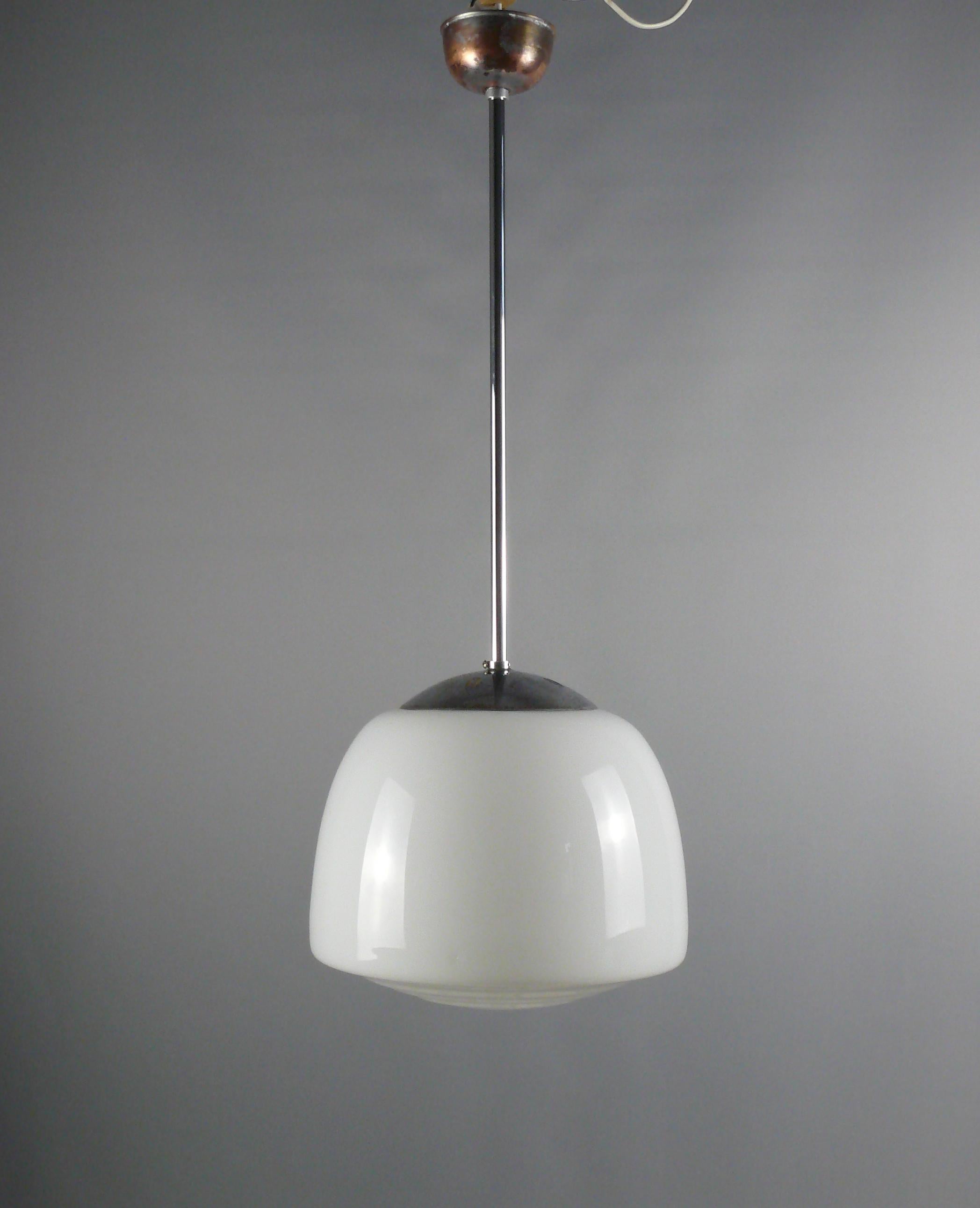 Elegant Bauhaus pendant lights with chrome-plated suspension and stepped, trapezoidal opal glass lampshade. The lamp dates from the first half of the 20th century. The opal glass shade is in good condition. Rod, socket and electrics renewed*. Canopy