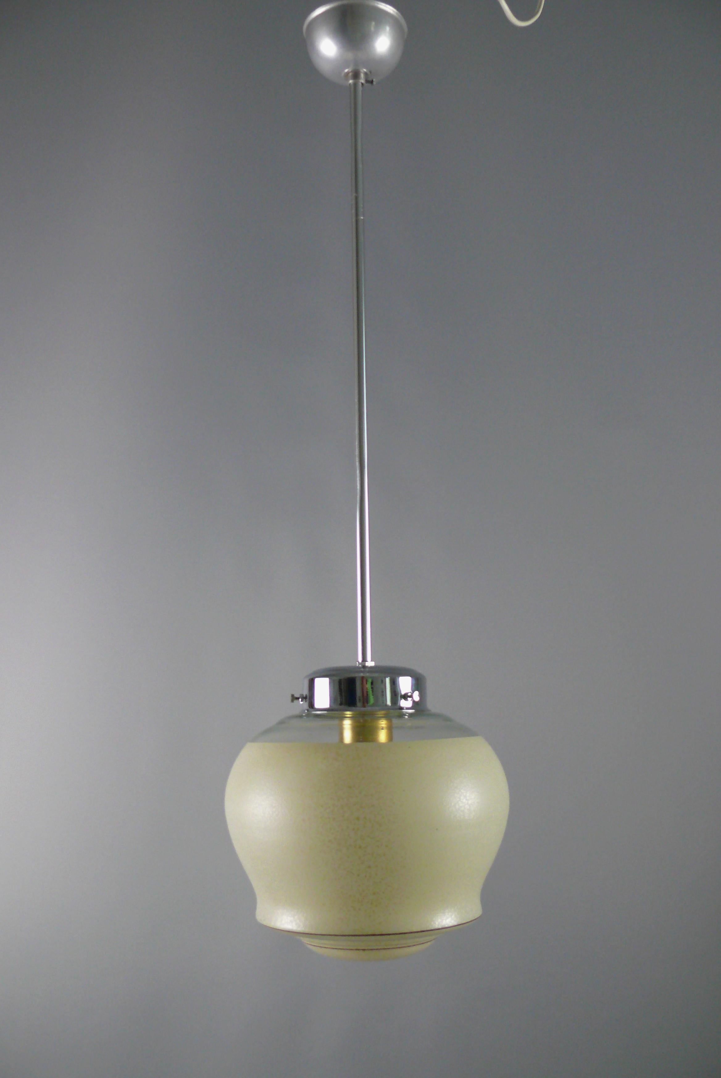 Art Deco rod pendant light from the 1930s - 1950s with a very beautiful profiled glass shade. The glass shade has radial decorative stripes, the lower part has a dotted beige lacquer, similar to pointillism, the upper part is transparent and is in