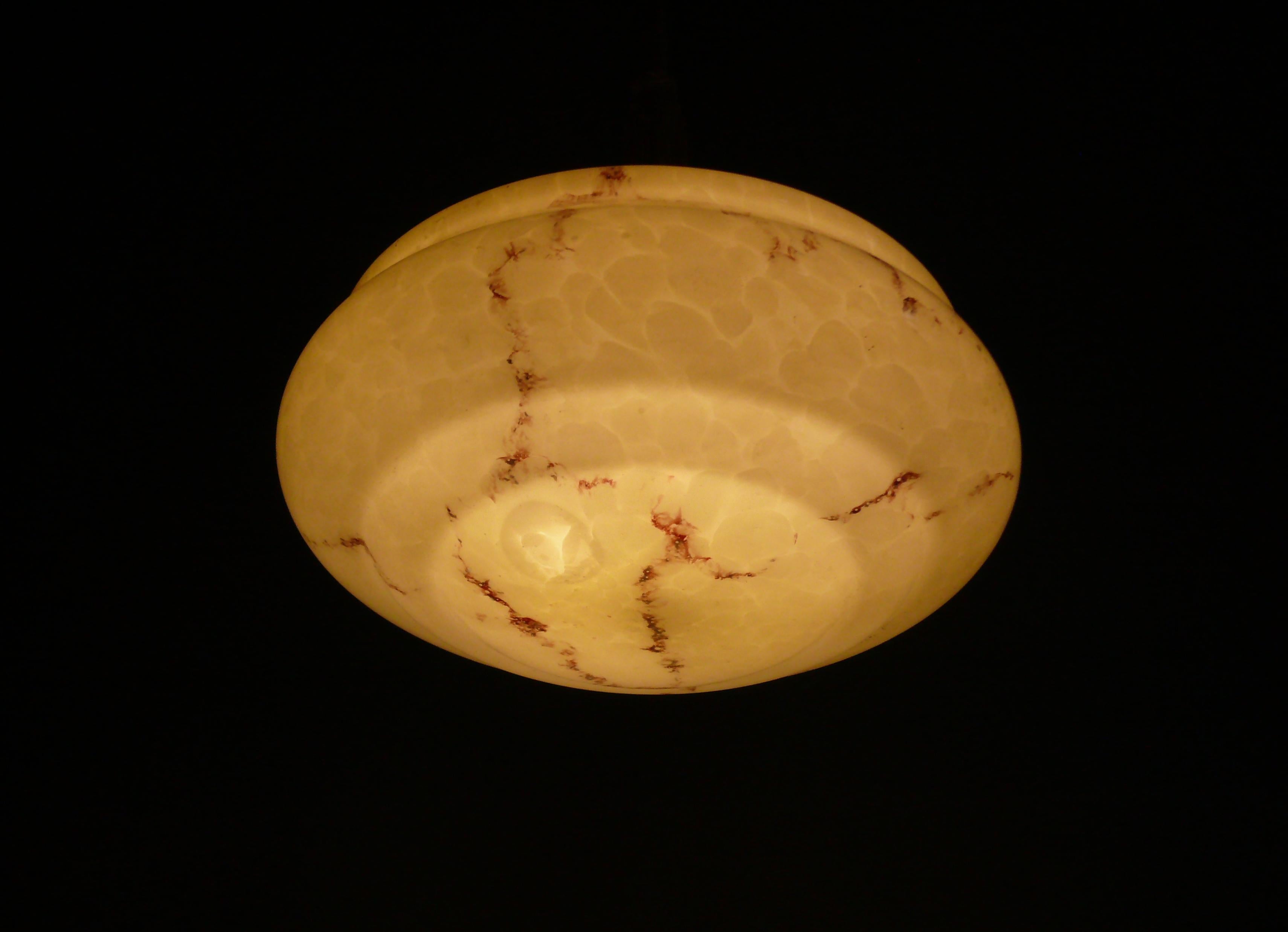Elegante lámpara colgante de varilla Art Decó beige de la primera mitad del siglo pasado -años 30- con pantalla de cristal jaspeado y varilla larga y enrollada.  

Esta lámpara colgante de varilla queda especialmente bien en apartamentos antiguos de