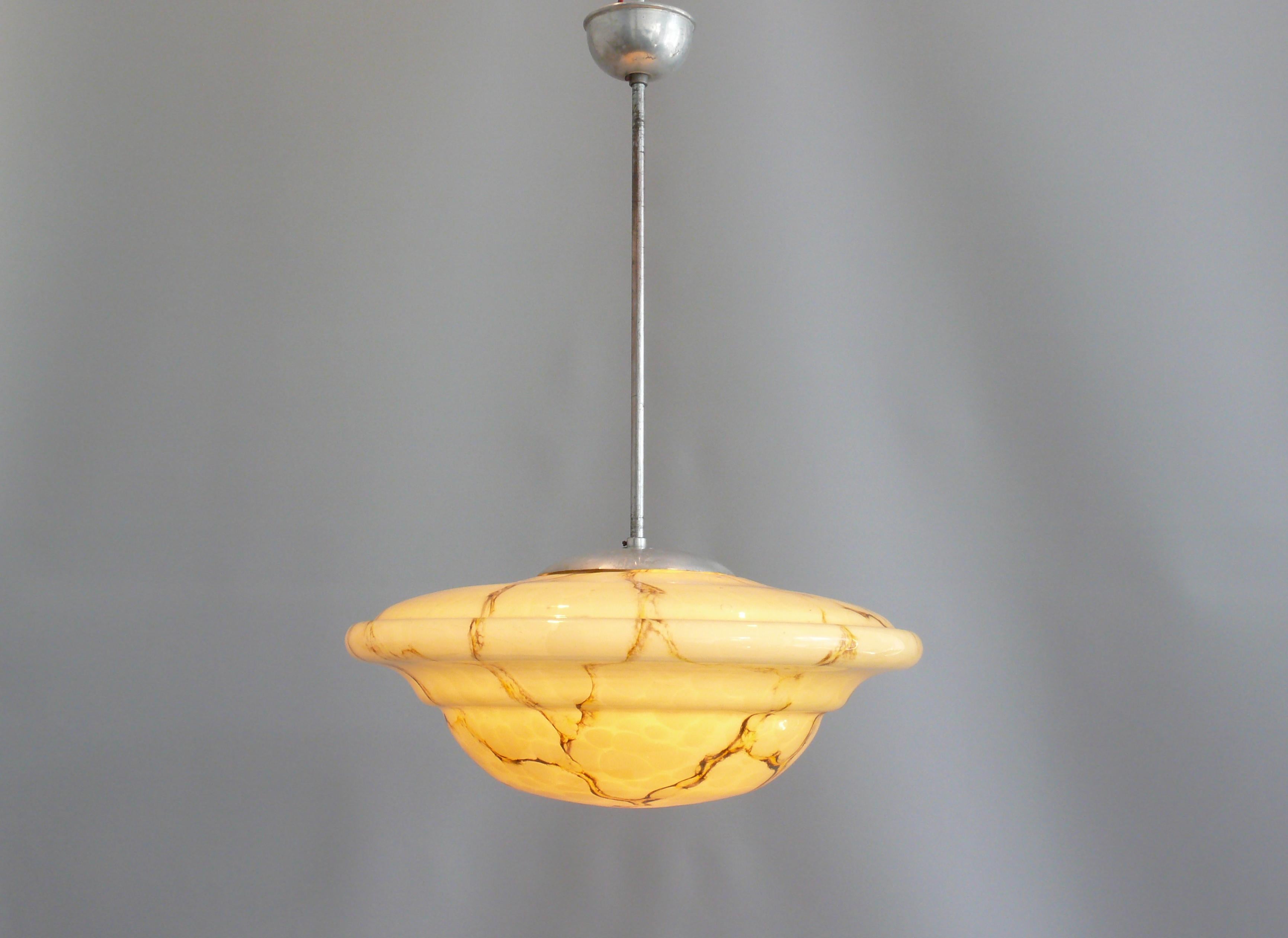 Large Art Deco pendant lamp with a profiled glass shade and silver suspension. The large, marbled glass shade is in very good condition and has a beautiful curve. The socket is made of brass, the ceiling suspension is made of metal. The lamp dates