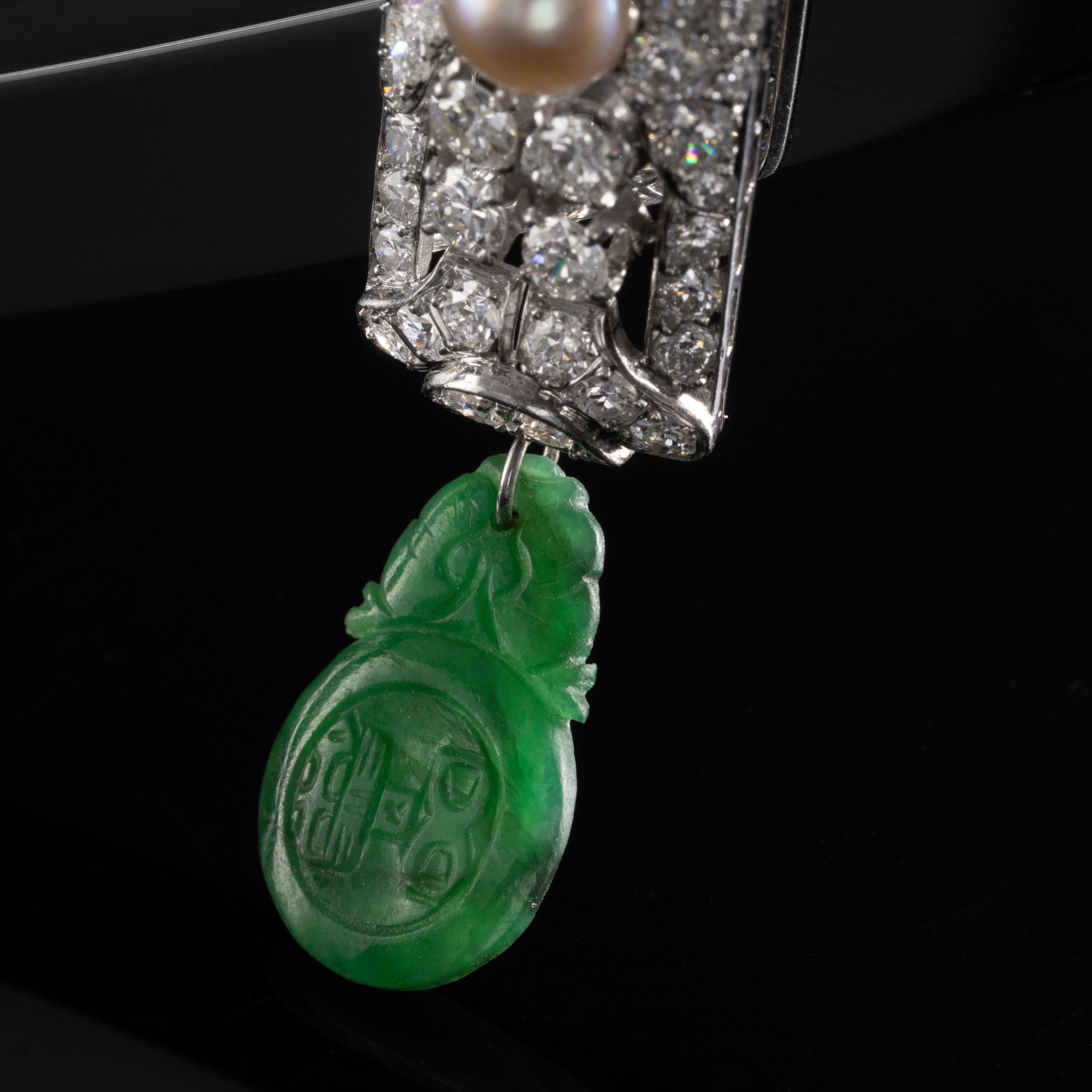 This Art Deco pendant necklace —ablaze in old diamonds— features two of the rarest and most precious gems on earth: natural pearl and natural, untreated jadeite jade. The sleek and permanently-stylish platinum Art Deco jewel is composed of two