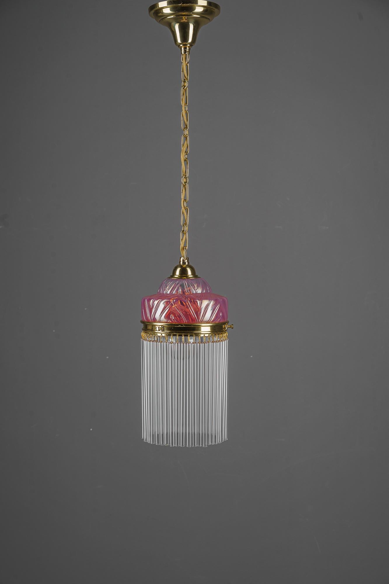 Suspension Art Déco avec abat-jour en verre opalin et bâtonnets en verre vienne vers 1920
Laiton poli et émaillé au four
Abat-jour original en verre opalin
Les bâtons de verre sont remplacés (neufs).