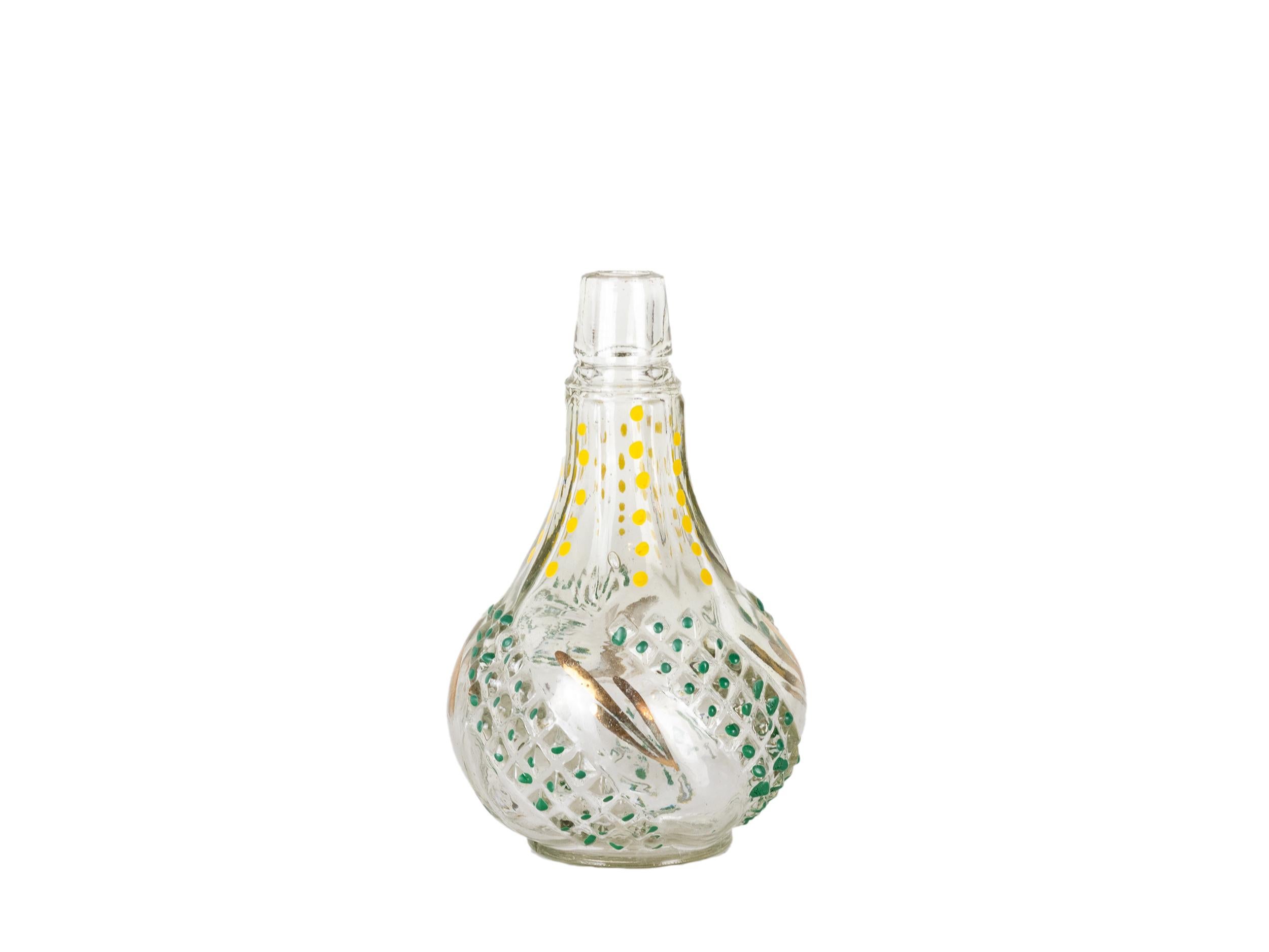 Questa delicata bottiglia di vetro per profumi della metà del secolo scorso presenta un design unico dipinto a mano in giallo, verde e oro. La sua forma organica a bulbo e la texture decorativa in rilievo riflettono l'artigianato tradizionale di