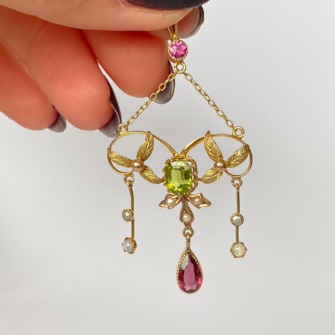 This suffragette pendant holds pink tourmaline, Peridot, Pearl and Opal and is modelled in 9carat gold. Either side of the peridot stone are trios of beautifully detailed leaves. 

Pendant top to bottom: 5.5cm

Weight: 2.7g