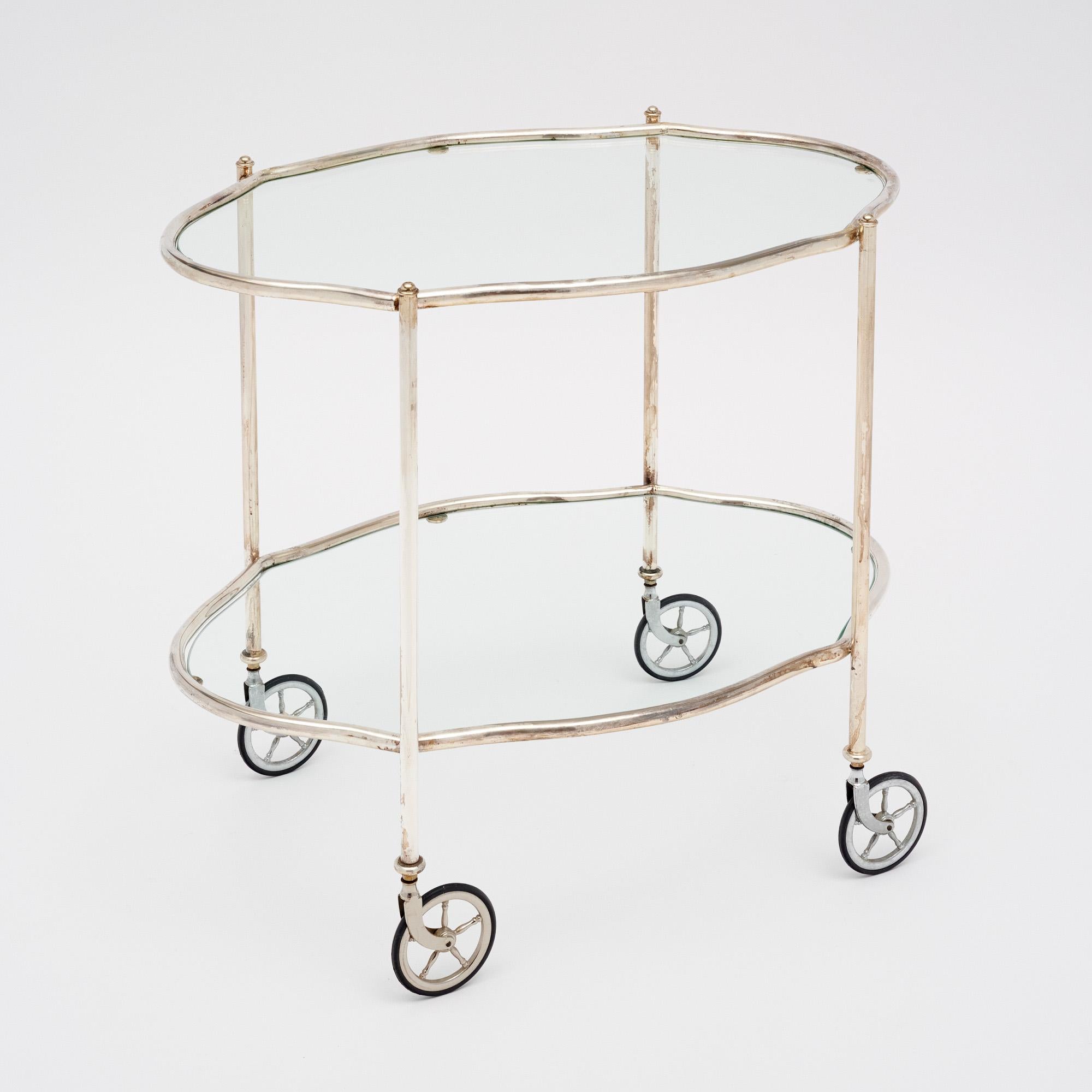 Bar cart from the Art Deco period in France. This piece is made with a solid brass structure featuring a silver plated finish. There are two glass shelves and four original casters. We were drawn to the striking Art Deco period shape of the bar