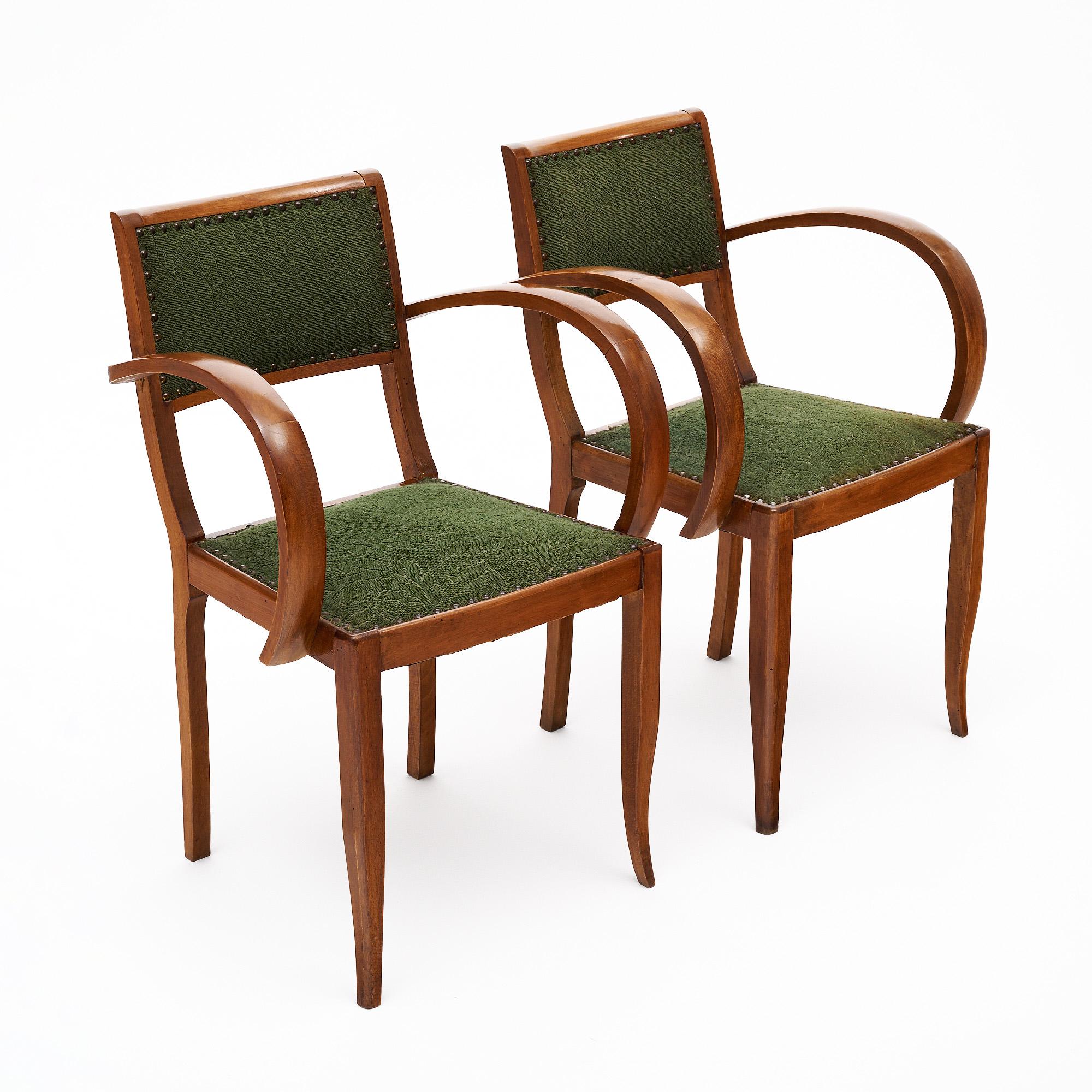 Paire de chaises latérales à pont de la période Art Déco en France. Ces chaises sont fabriquées à la main avec des cadres en noyer massif qui ont été finis avec un poli français lustré. Nous aimons les accoudoirs incurvés qui évoquent le style Art