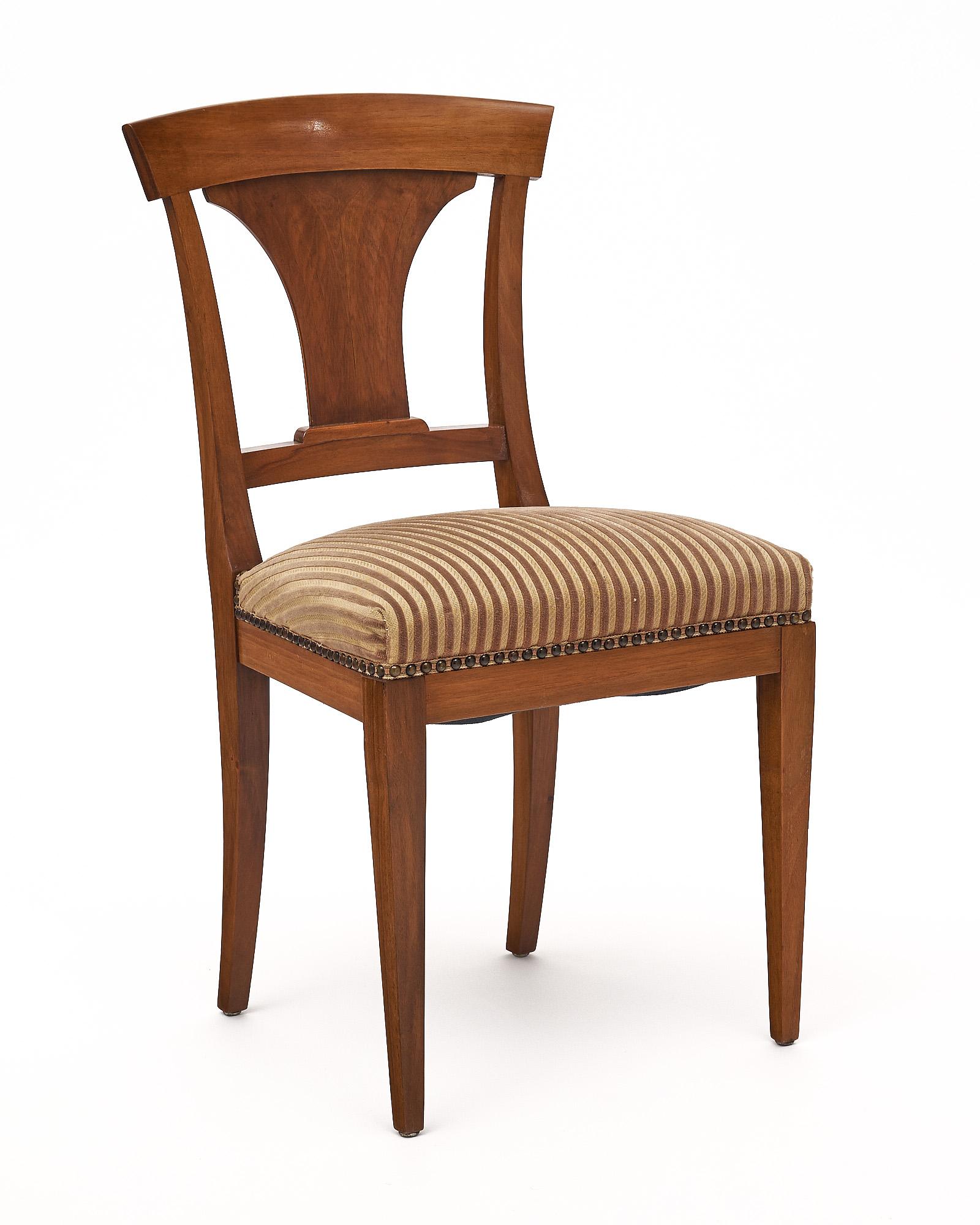 Conjunto de seis sillas de comedor fabricadas con estructura de nogal y tapicería original. Se han acabado con un lustroso pulido francés de calidad de museo. La tapicería está adornada con tachuelas de latón alrededor de la base de los asientos.