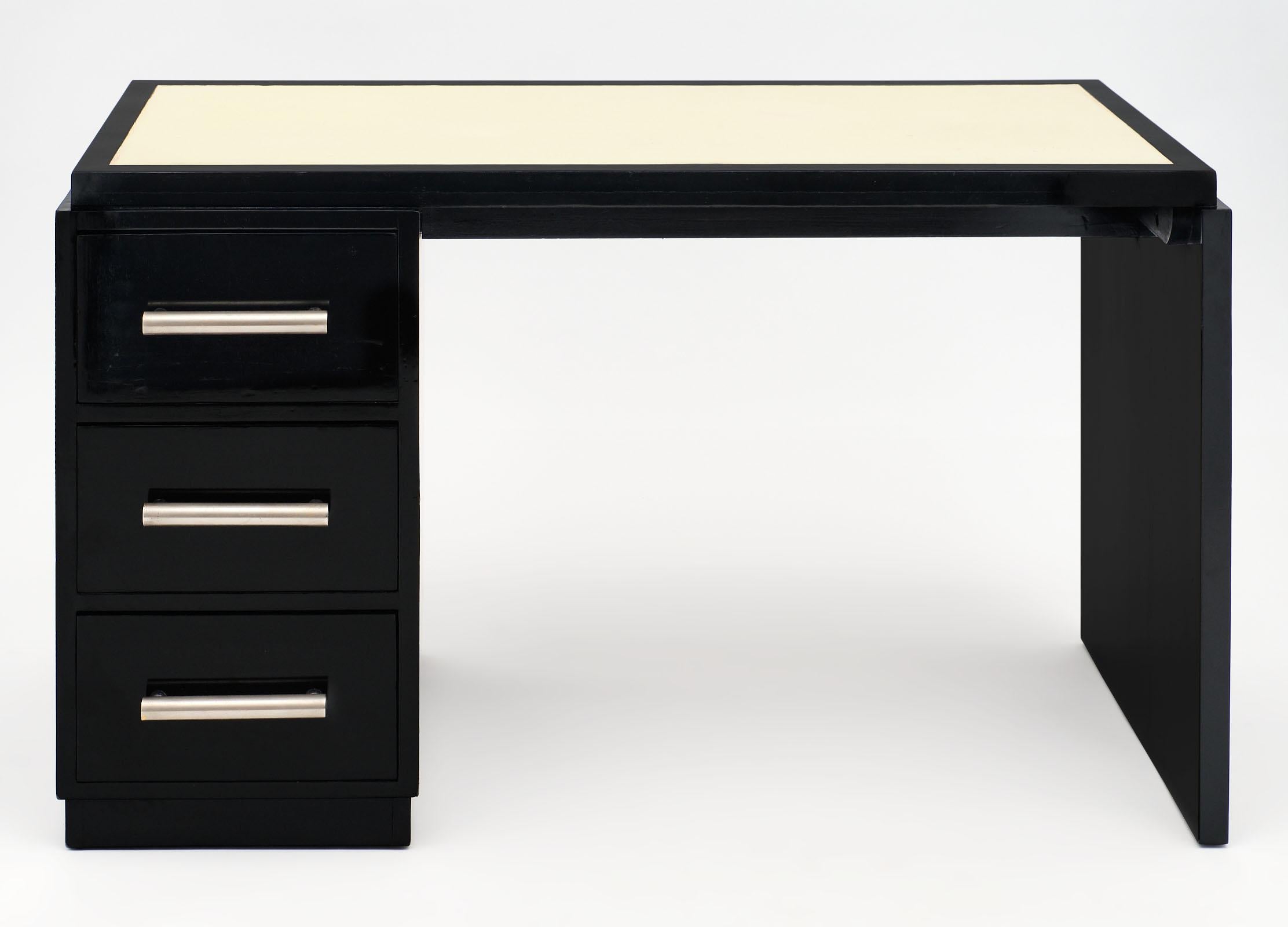 French Art Deco period ebonized desk with great lines and three dovetailed drawers with original pulls. The top has a cream leather writing surface. We love the ebonized oak and impressive impact of this piece.