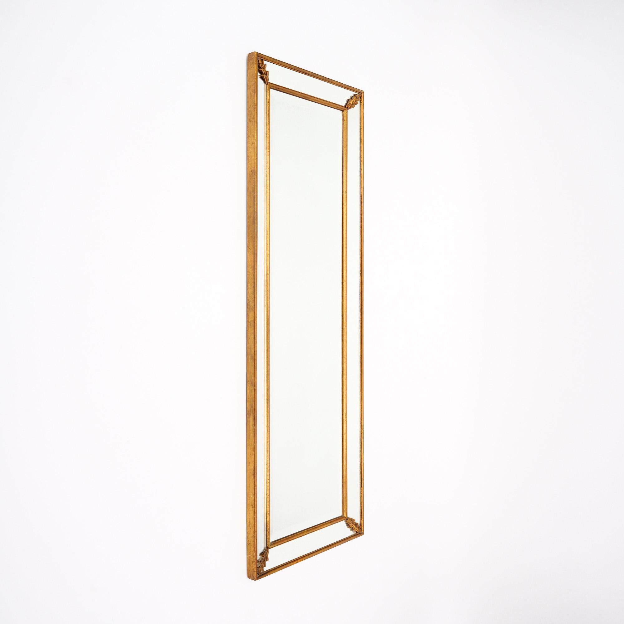 Art Deco period mirror from France. The mirror has a central full length rectangular mirror in the center. The pareclose frame has a wood gold-leafed structure with mirror pieces held in place with stylized leaf details. The mirror in the center is